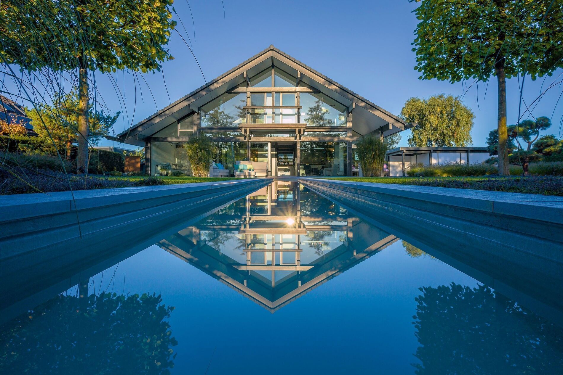 Fachwerkhaus aus Holz und Glas mit Bachlauf und Spiegelung im Wasser