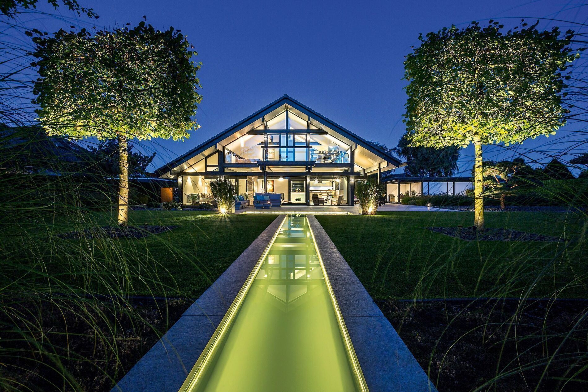 Transparente Architektur mit Holz und Glas, Garten mit Bachlauf bei Nacht