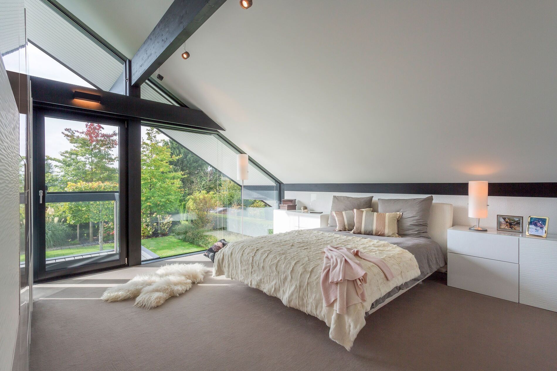 Helles Schlafzimmer mit Blick auf Garten und Glasbalkon