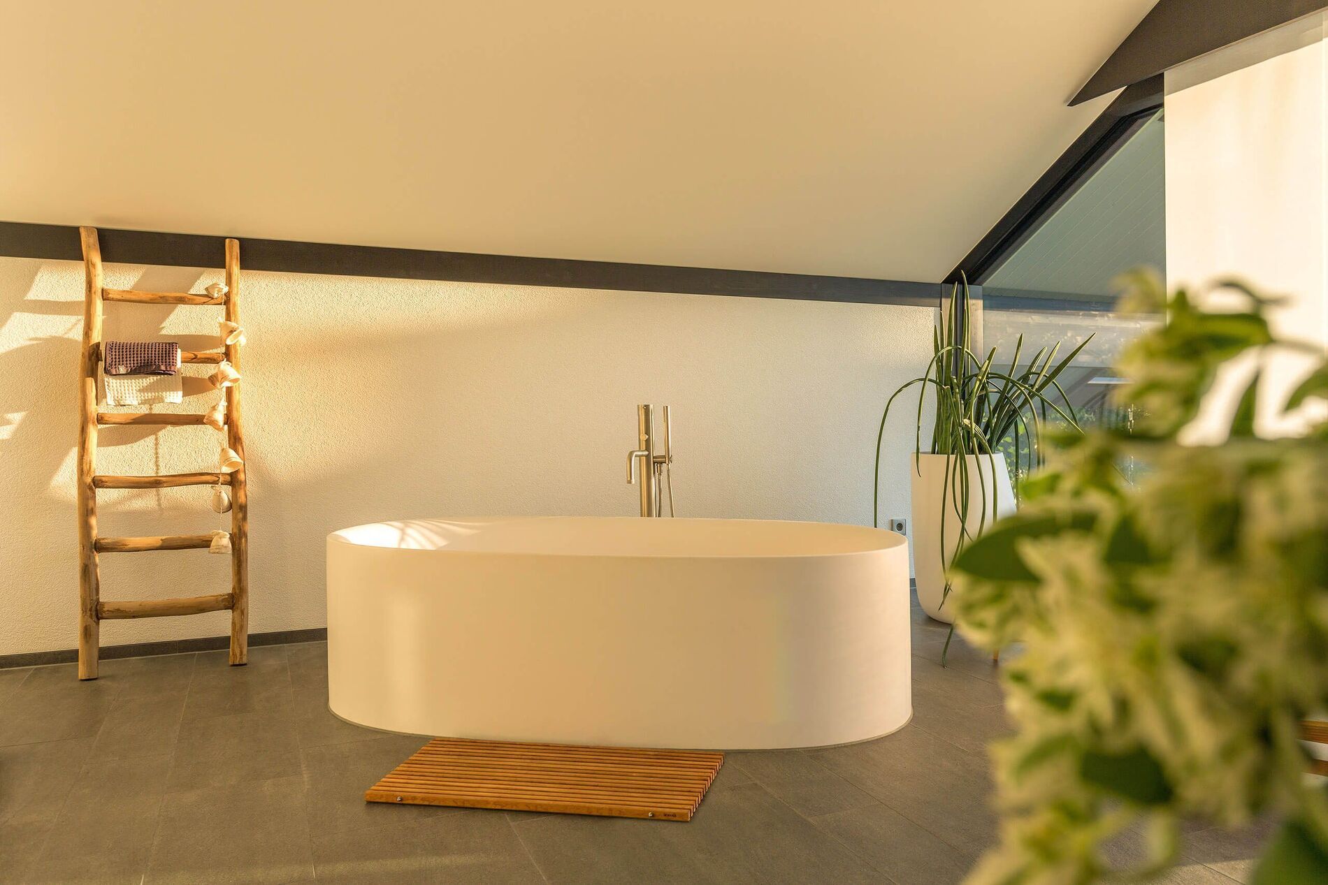Modernes Badezimmer mit ovaler Badewanne und Holzleiter