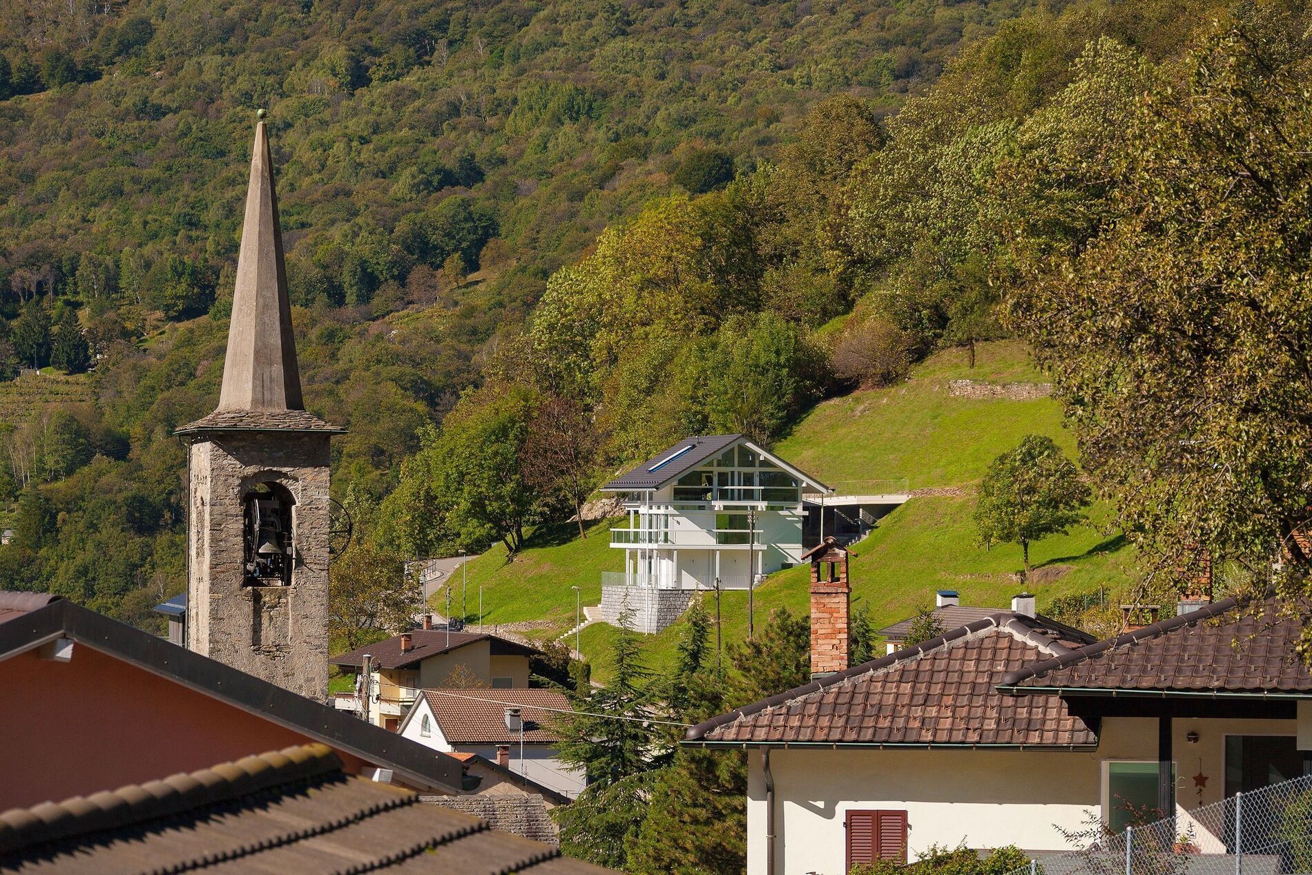 Modernes Haus perfekt in die Landschaft integriert, neben einem Kirchturm