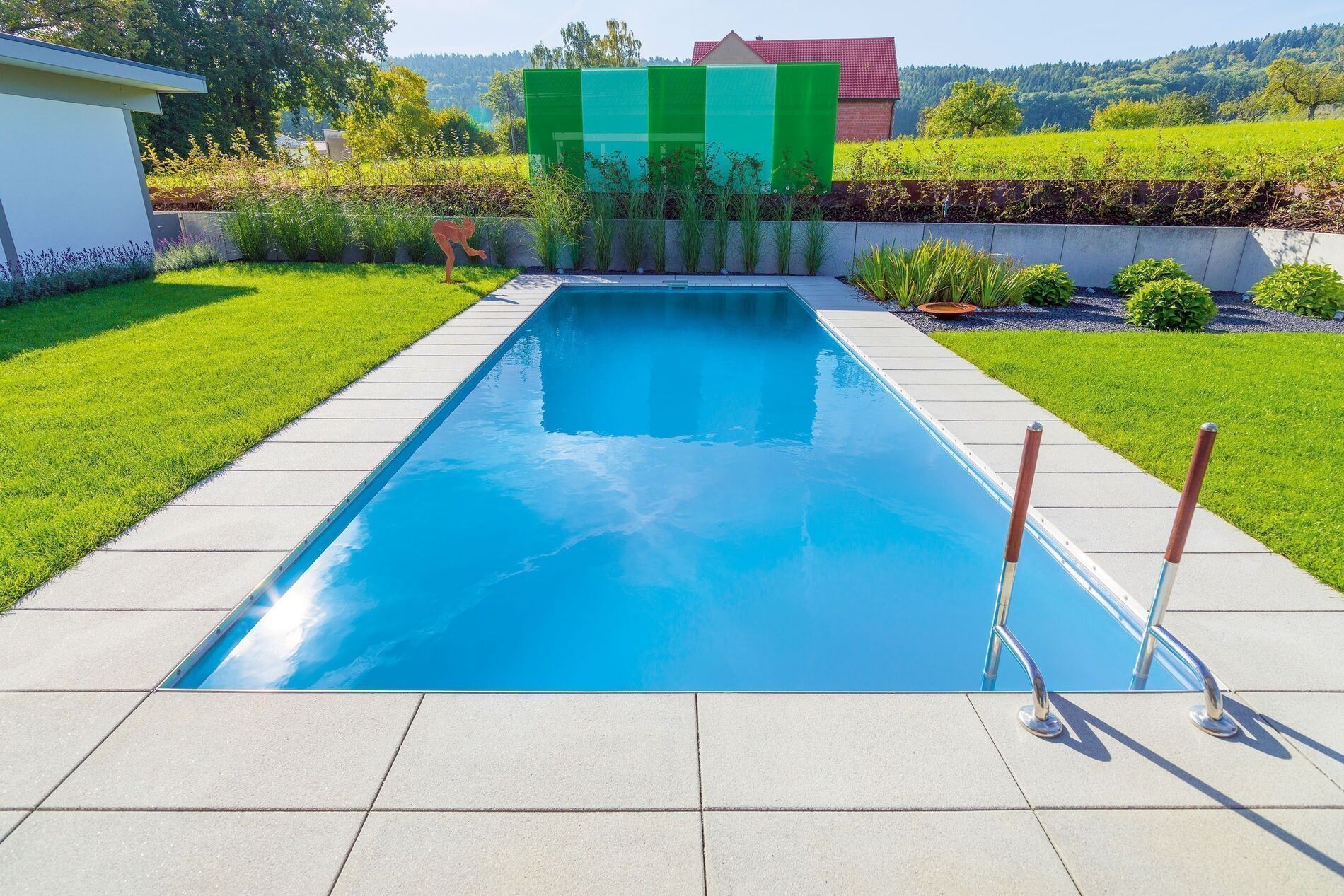 Ein HUF Haus mit einem blauen Pool und gepflegtem Garten.