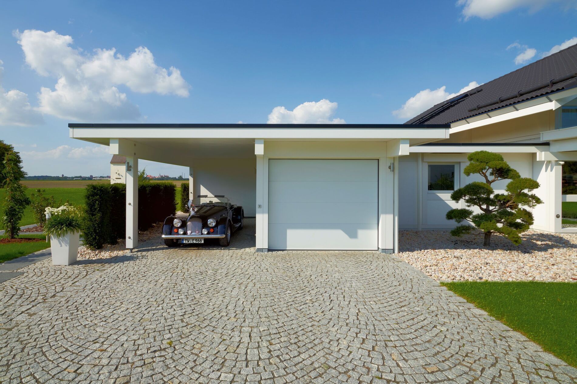 Modernes Fachwerkhaus mit Garage und Auto, umgeben von Natur