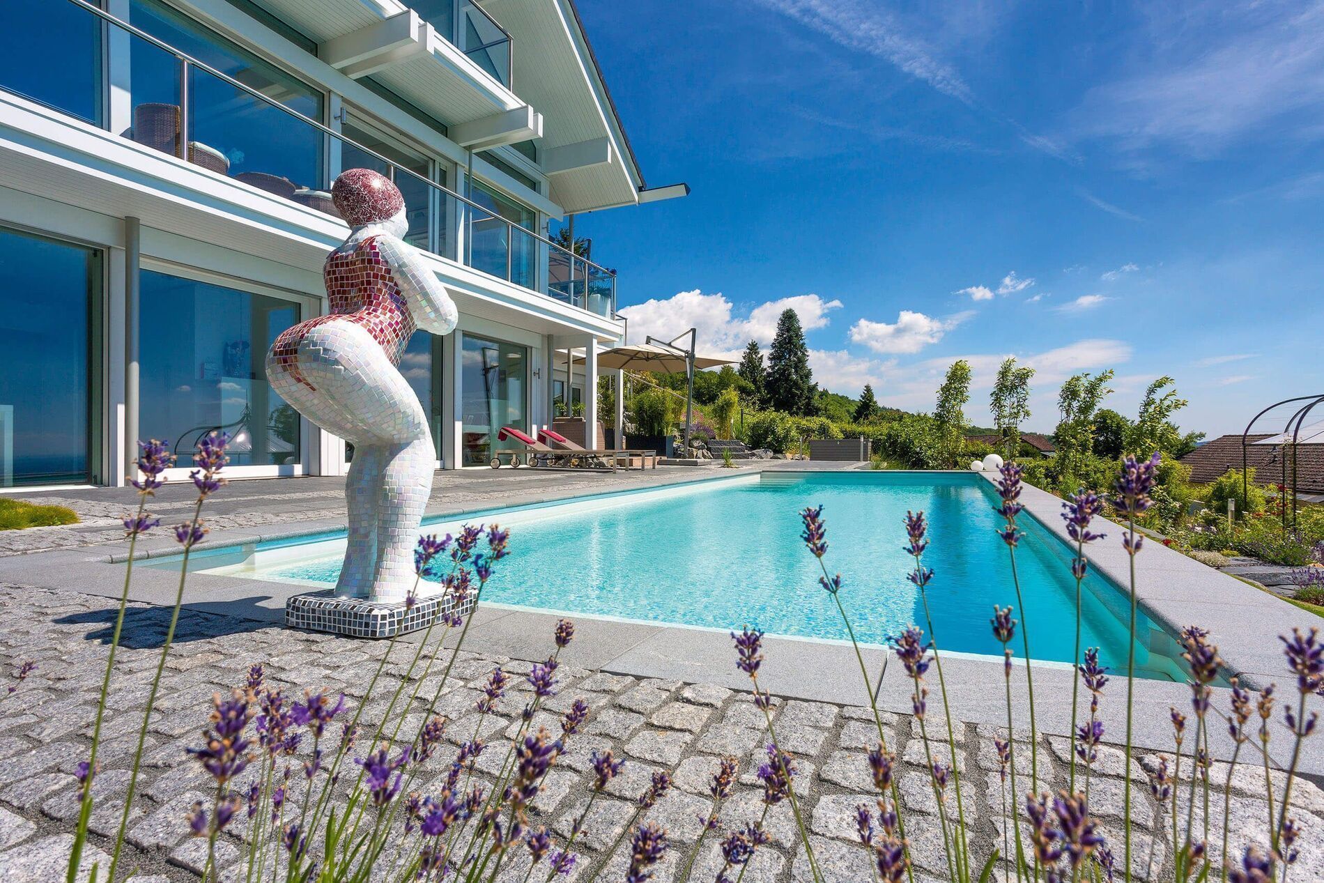 Modernes Designhaus mit Pool, Garten und Skulptur im Vordergrund