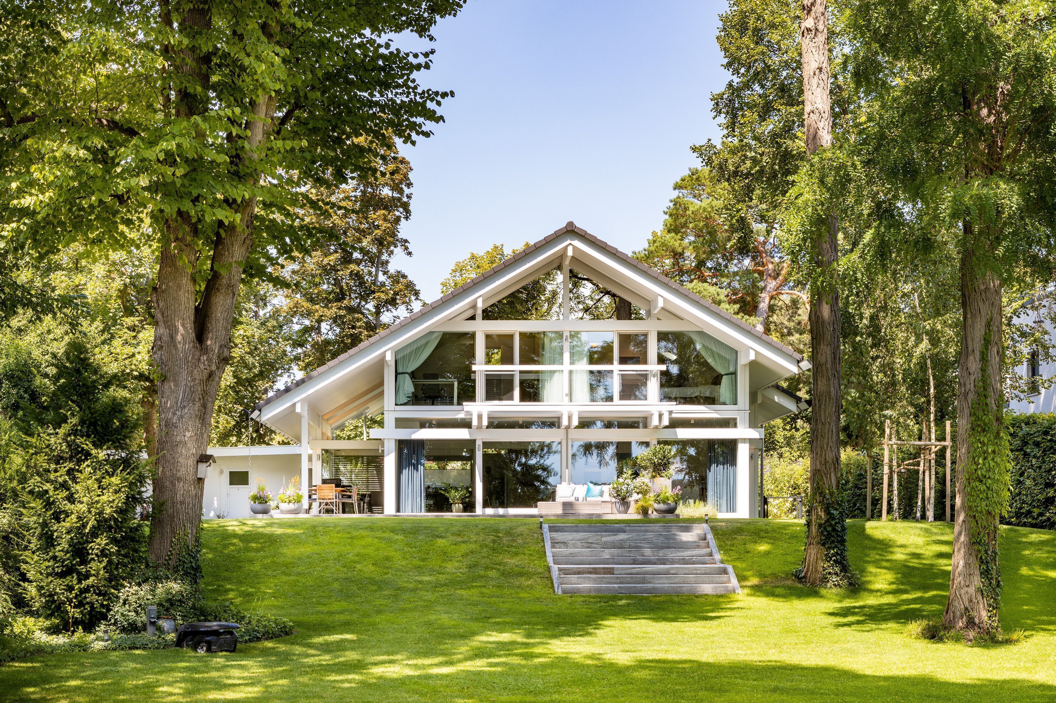 Architektenhaus im Grünen, umgeben von Bäumen und Rasen