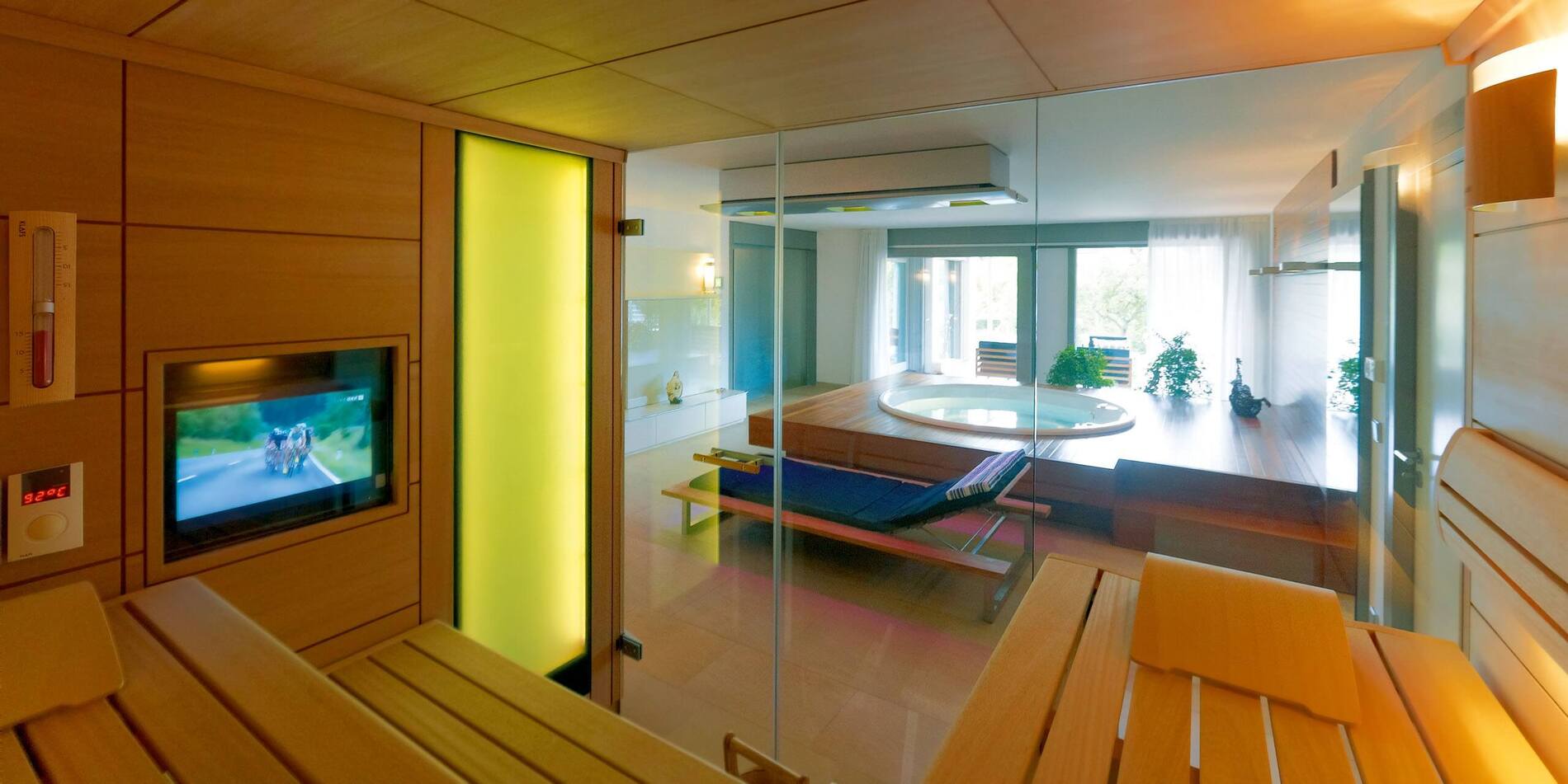 Innenansicht einer Sauna mit Glaswand und Blick auf einen Entspannungsbereich