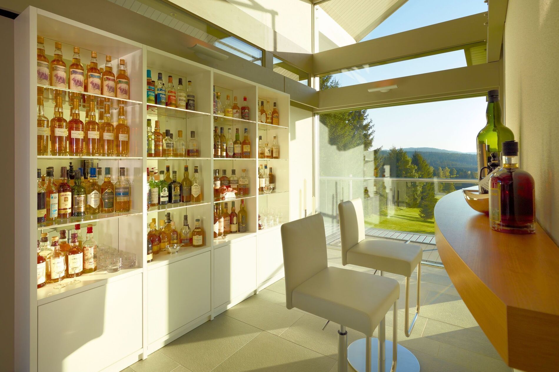 Stylische Bar mit einer Vielzahl von Spirituosen und Blick ins Grüne