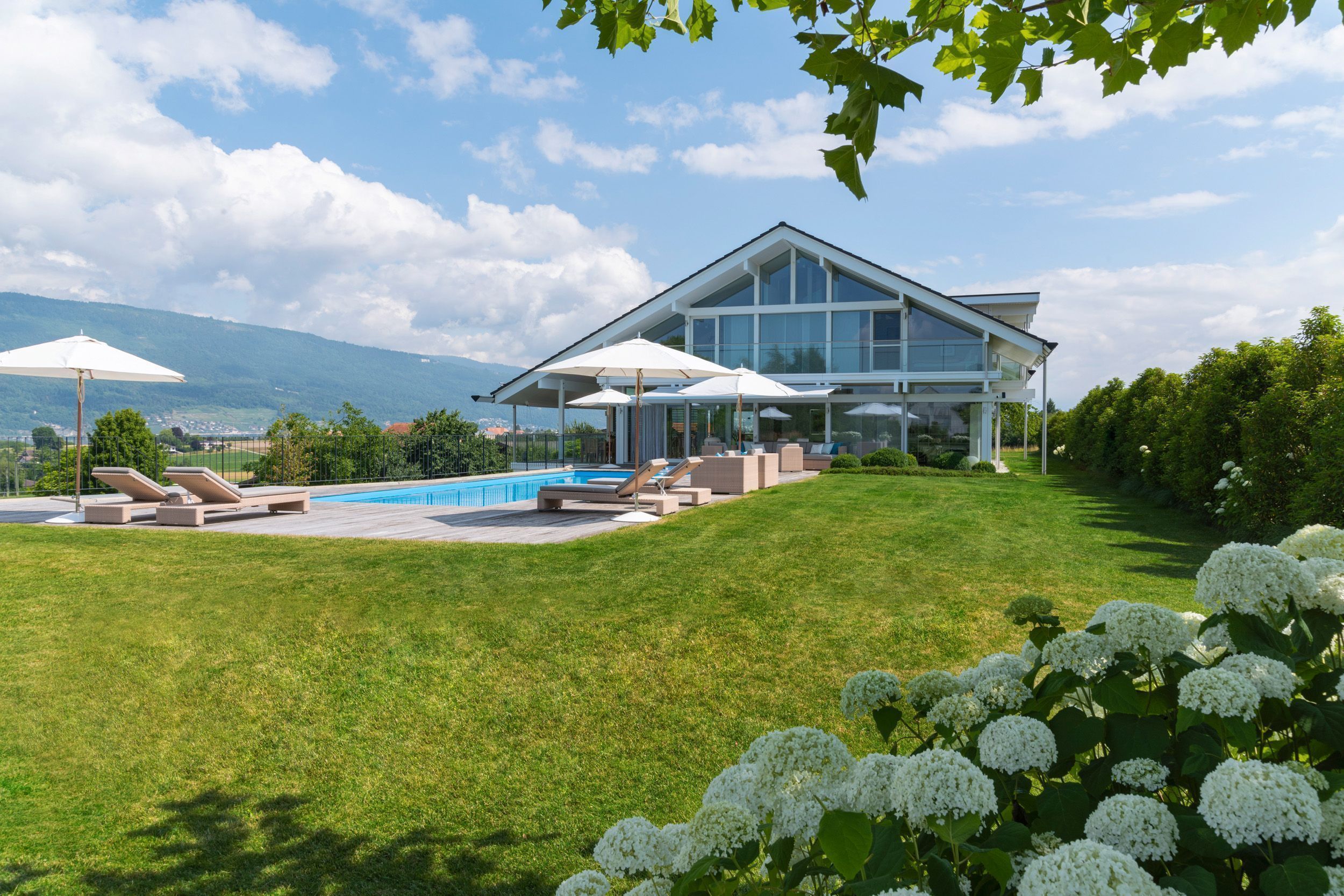 Schickes Haus mit Pool, Sonnenschirmen und grüner Umgebung