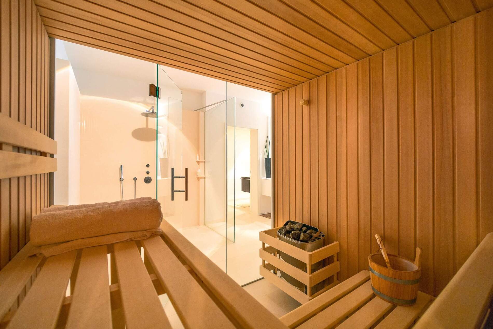 Gemütliche Sauna mit Holzbänken und Glasdusche in modernem Design