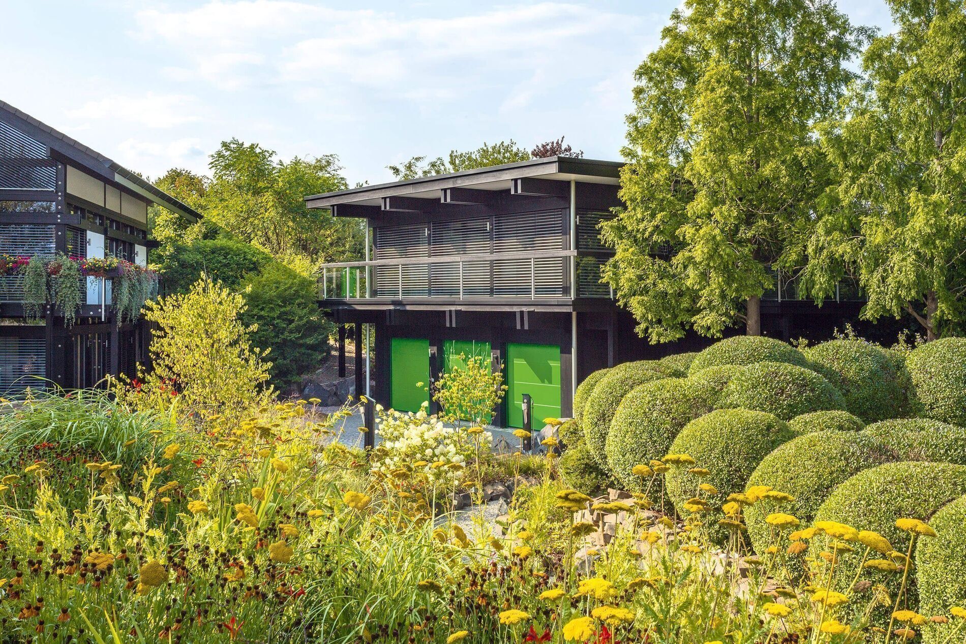 Modernes HUF Haus mit Dreifach-Garage und Bürogebäude Ansicht eines HUF Hauses mit gepflegtem Garten und Bürogebäude