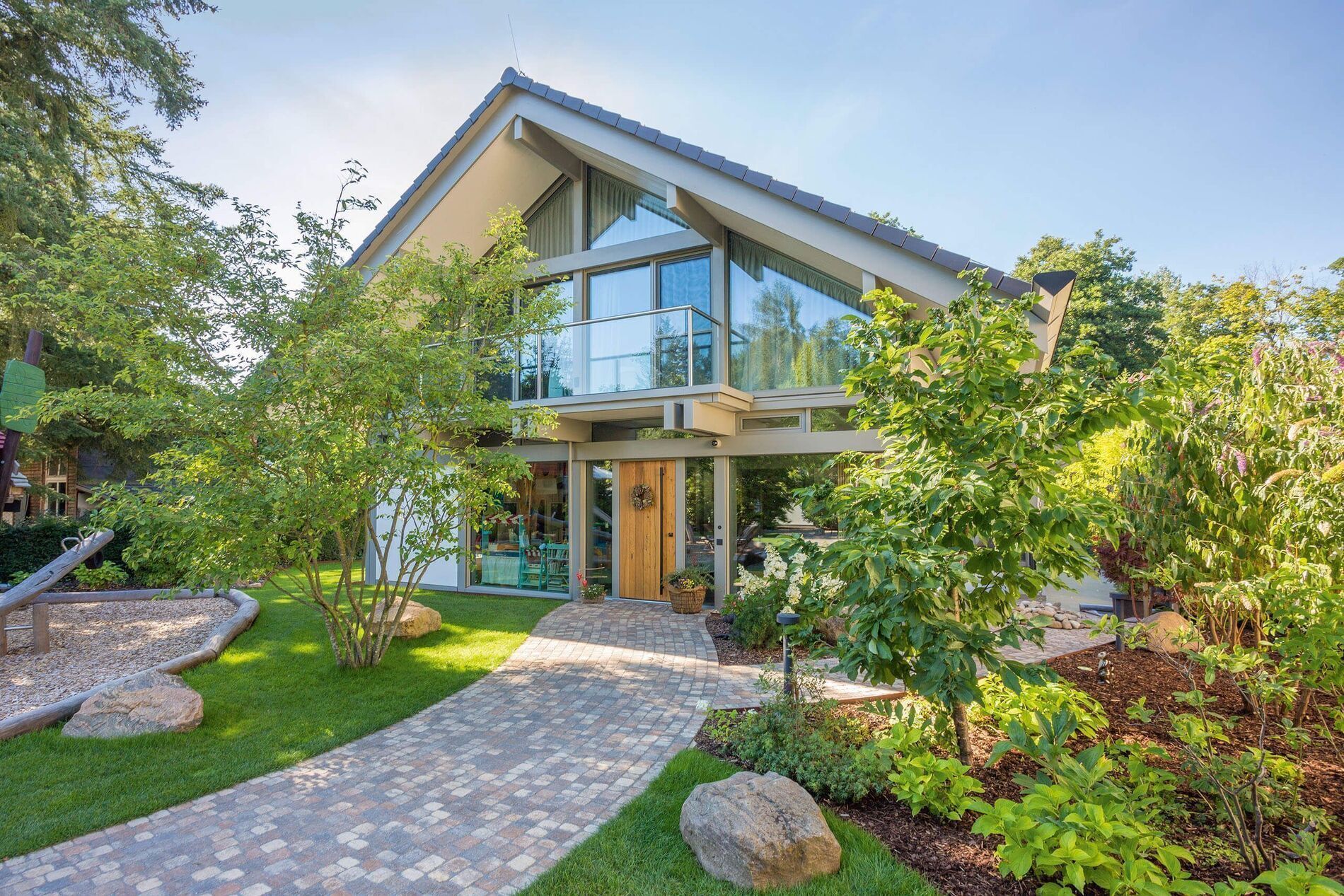 Modernes HUF Haus mit Giebel, Poolhaus und Garagenanlage in grünem Umfeld