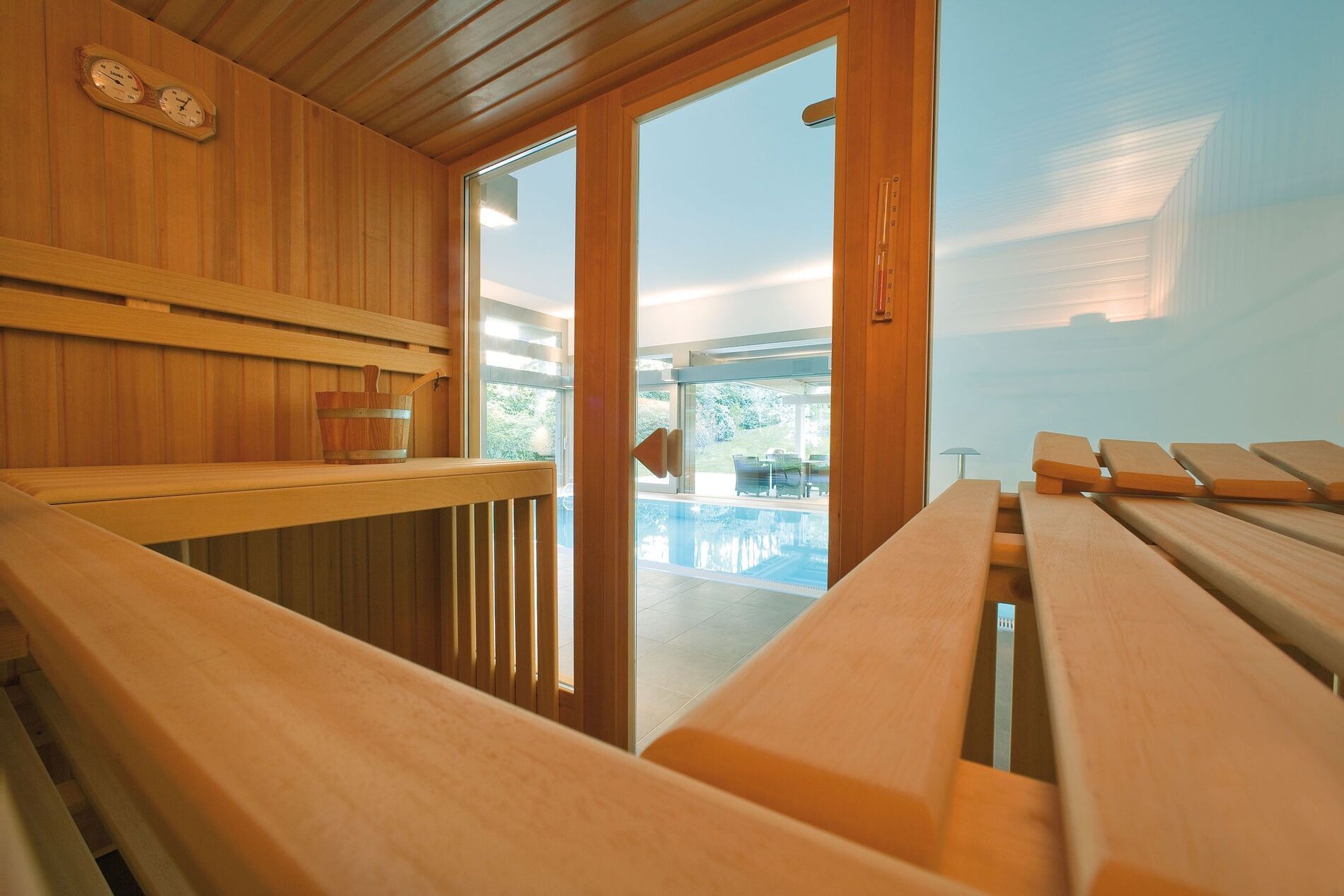 Moderne Sauna mit Poolblick in elegantem Design Innenansicht einer Sauna mit Holzelementen und Sicht auf den Pool