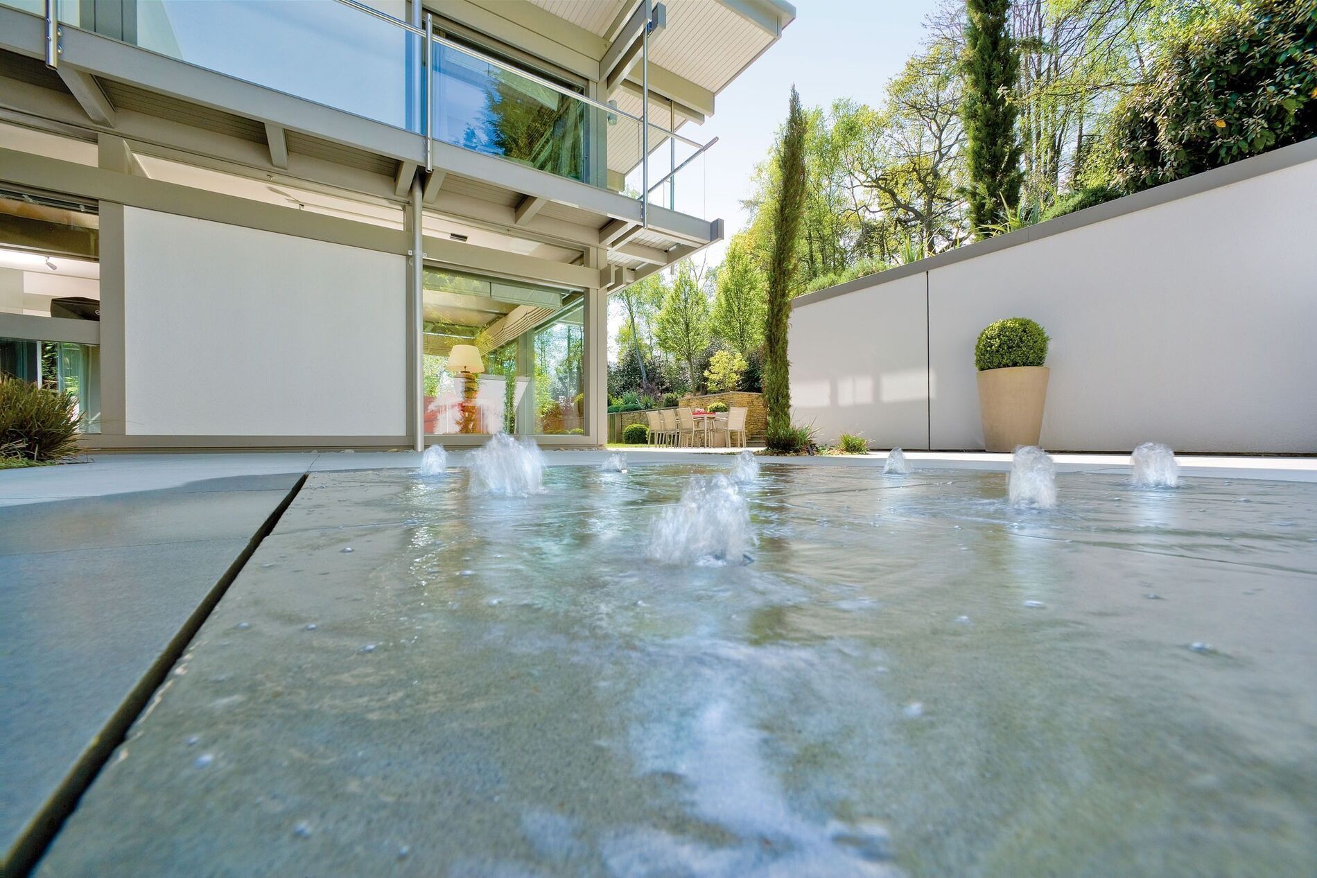 Exklusives modernes Flachdachhaus mit Wasserfontänen im Vordergrund