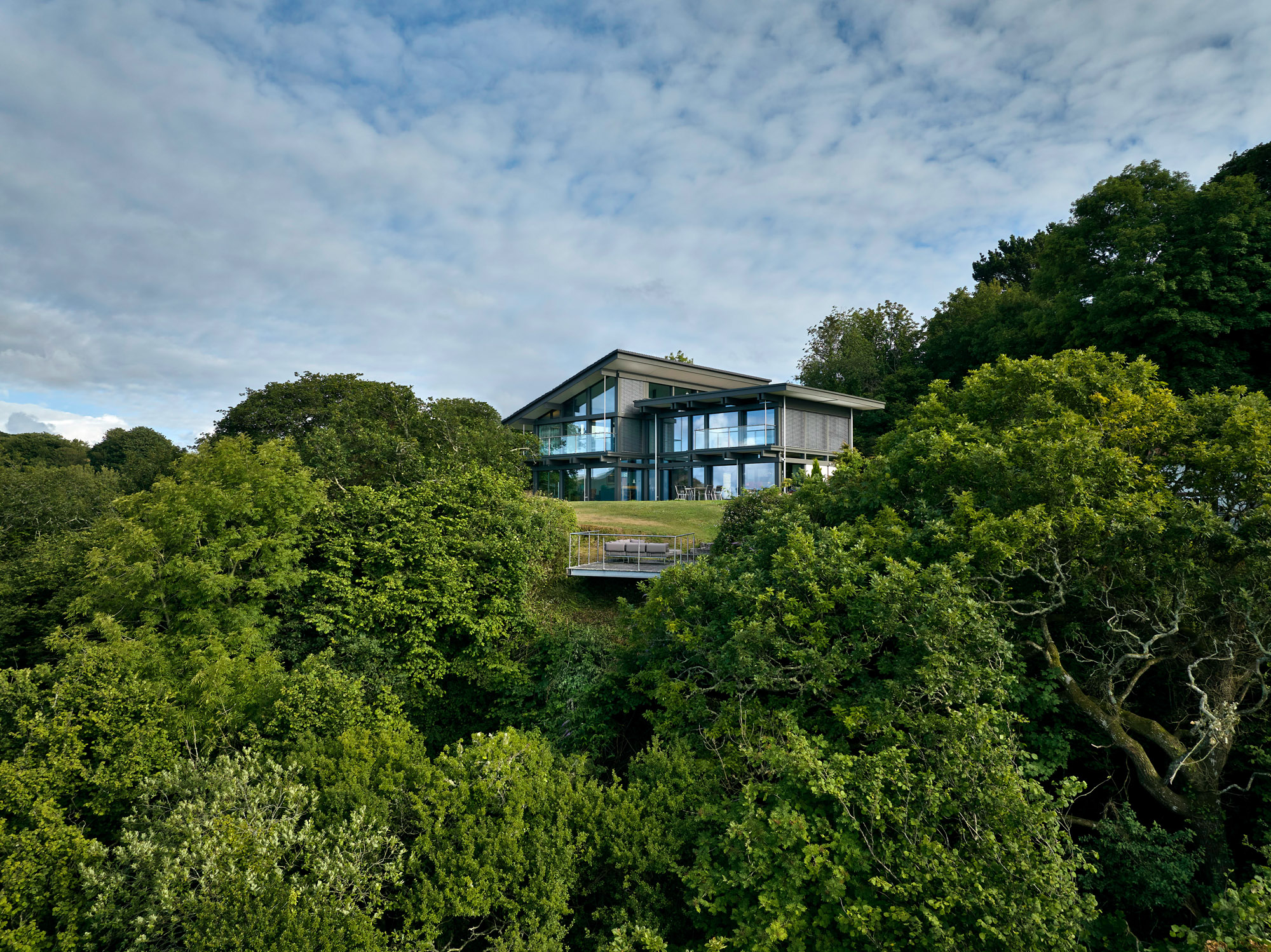 Modernes Haus umgeben von Bäumen, mit Glasfassade und schöner Aussicht