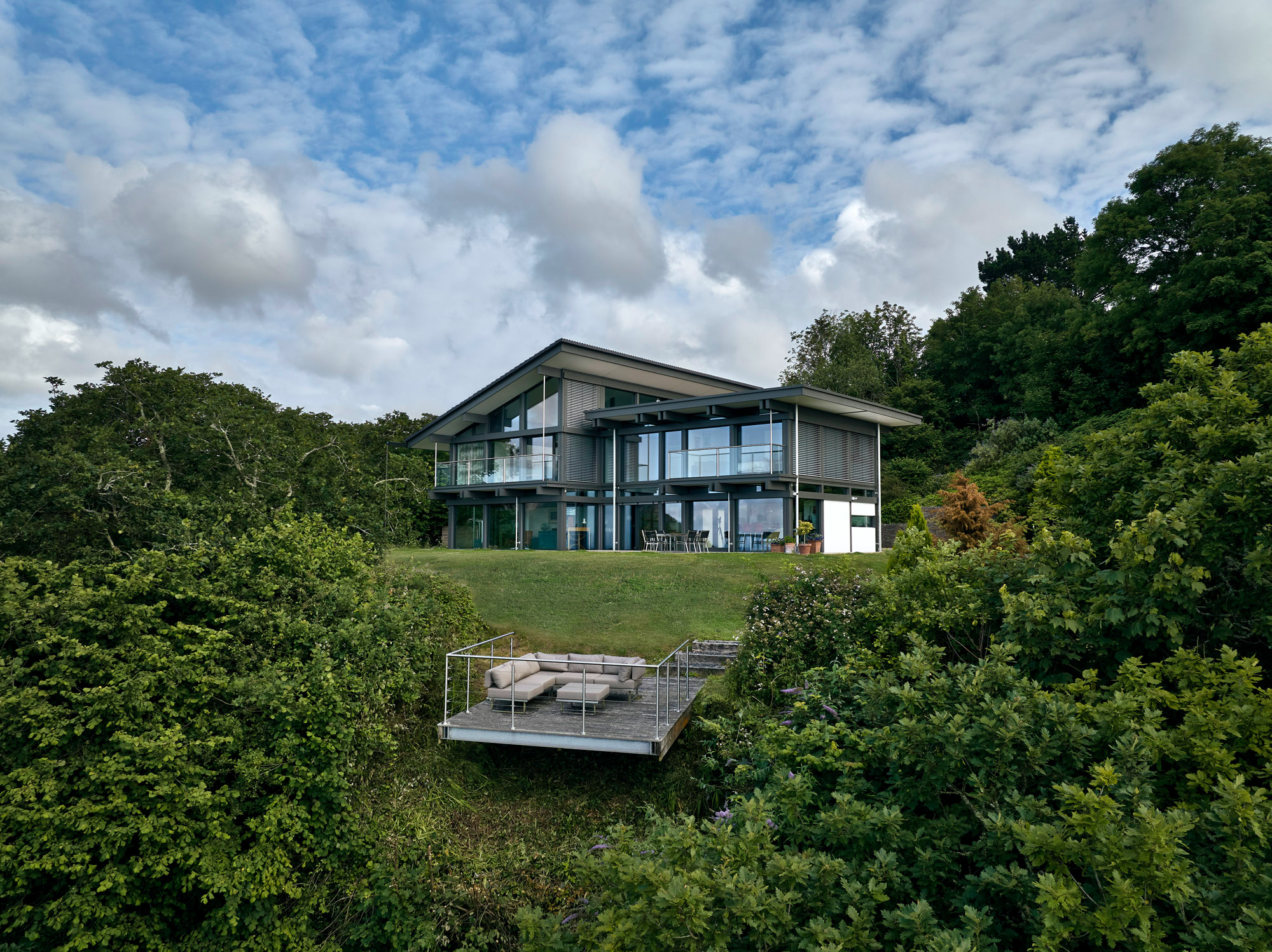 Ein modernes Designhaus am Meer mit großflächigen Fenstern und Garten.