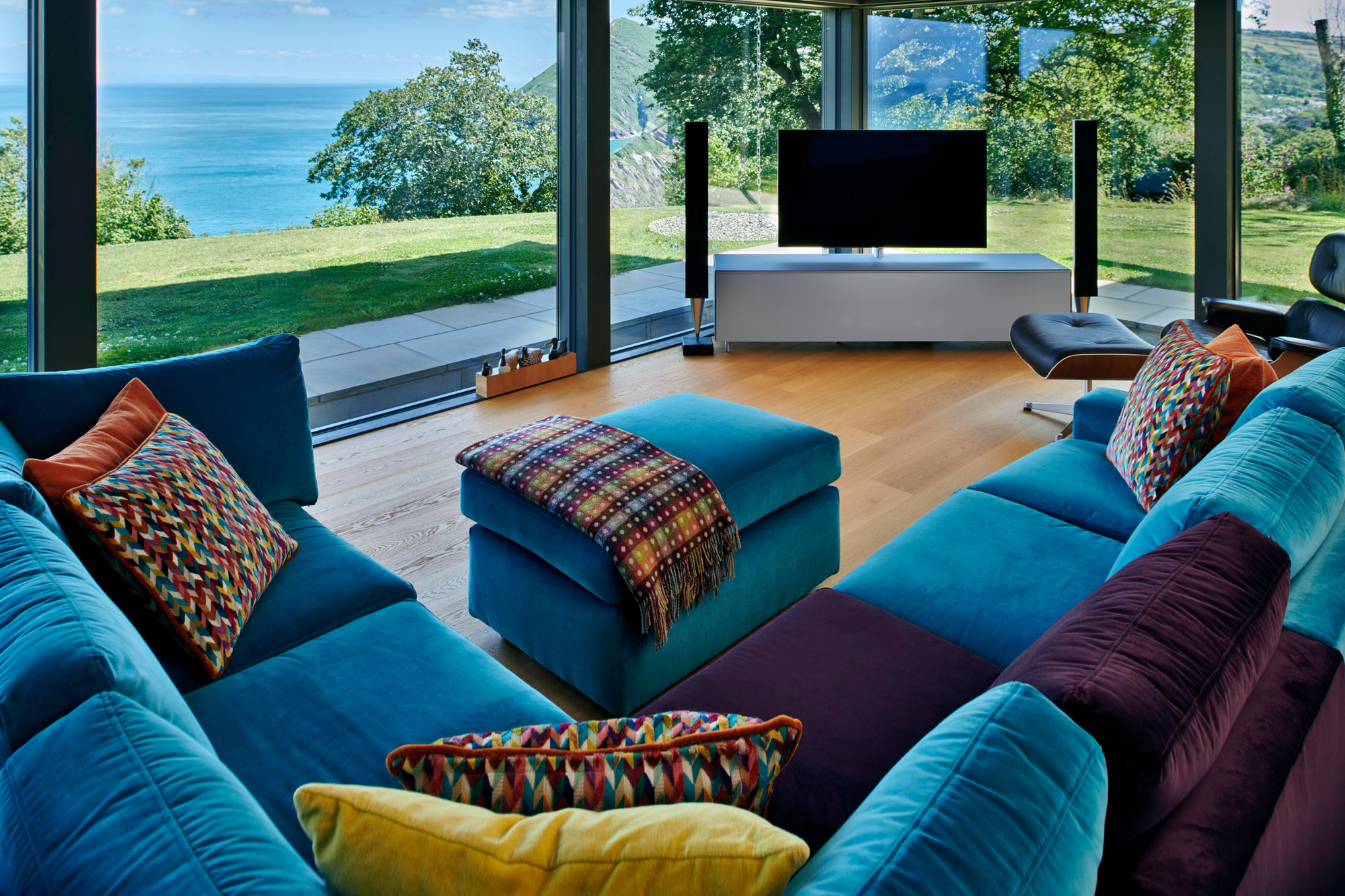 Stylisches modernes Wohnzimmer mit Blick auf das Meer und farbenfrohen Kissen