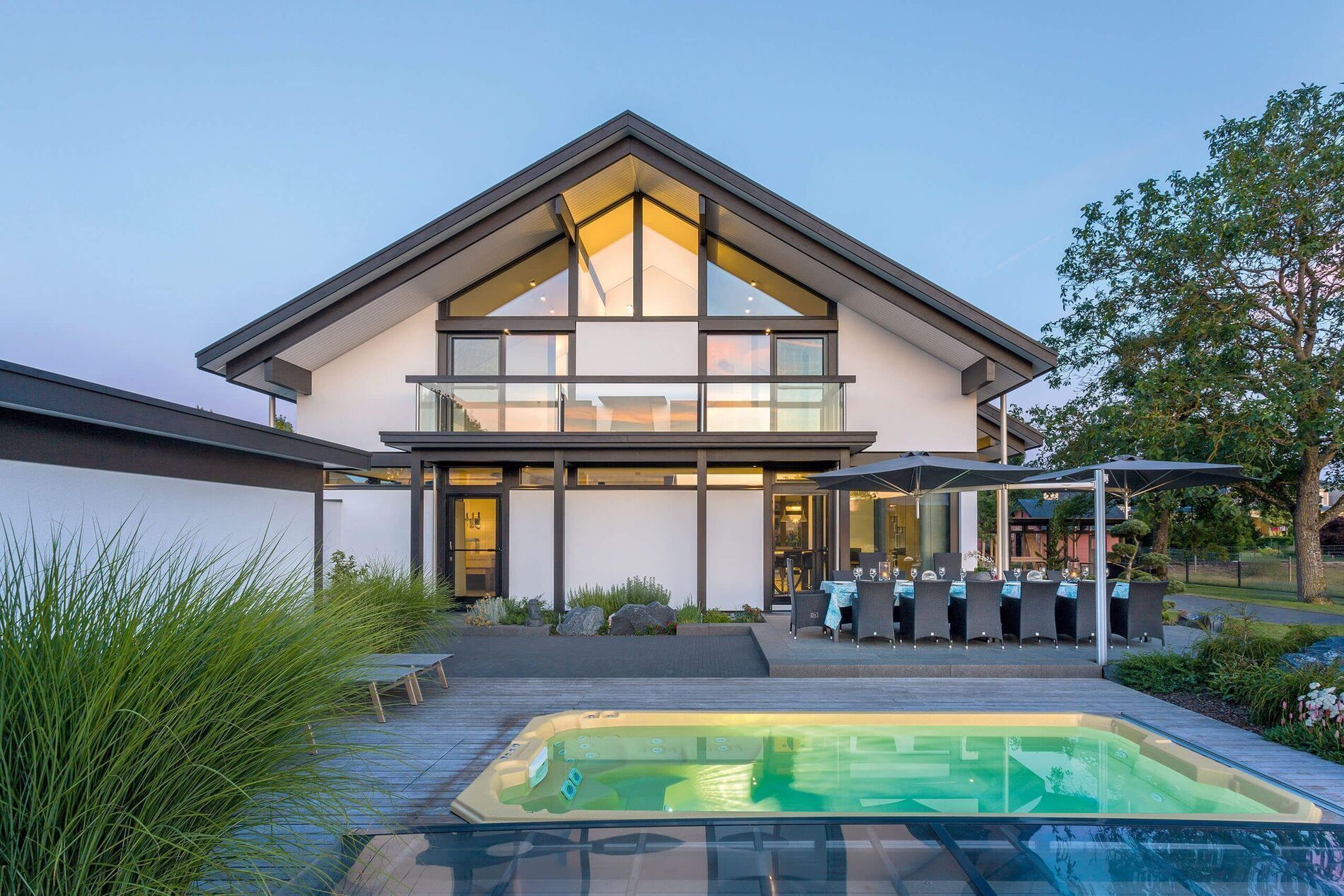Ein modernes Haus mit großen Fenstern und einem Swimmingpool im Vordergrund