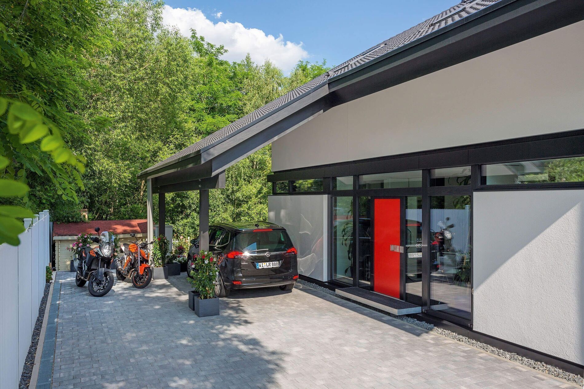 Elegantes Haus mit roter Tür, Garage und Pflanzen im Eingangsbereich