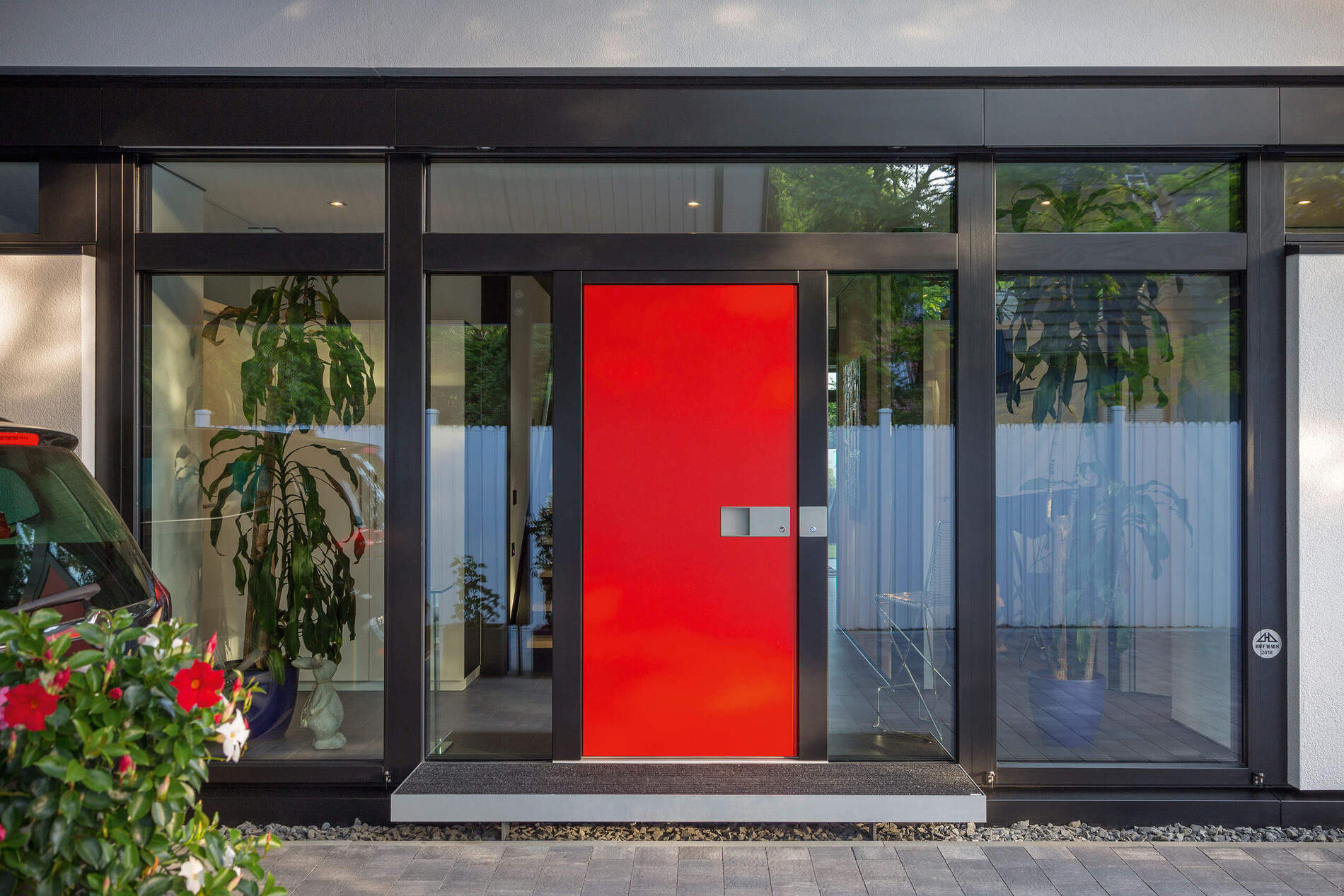 Eingangsbereich eines modernen Hauses mit Glasfront und roter Tür