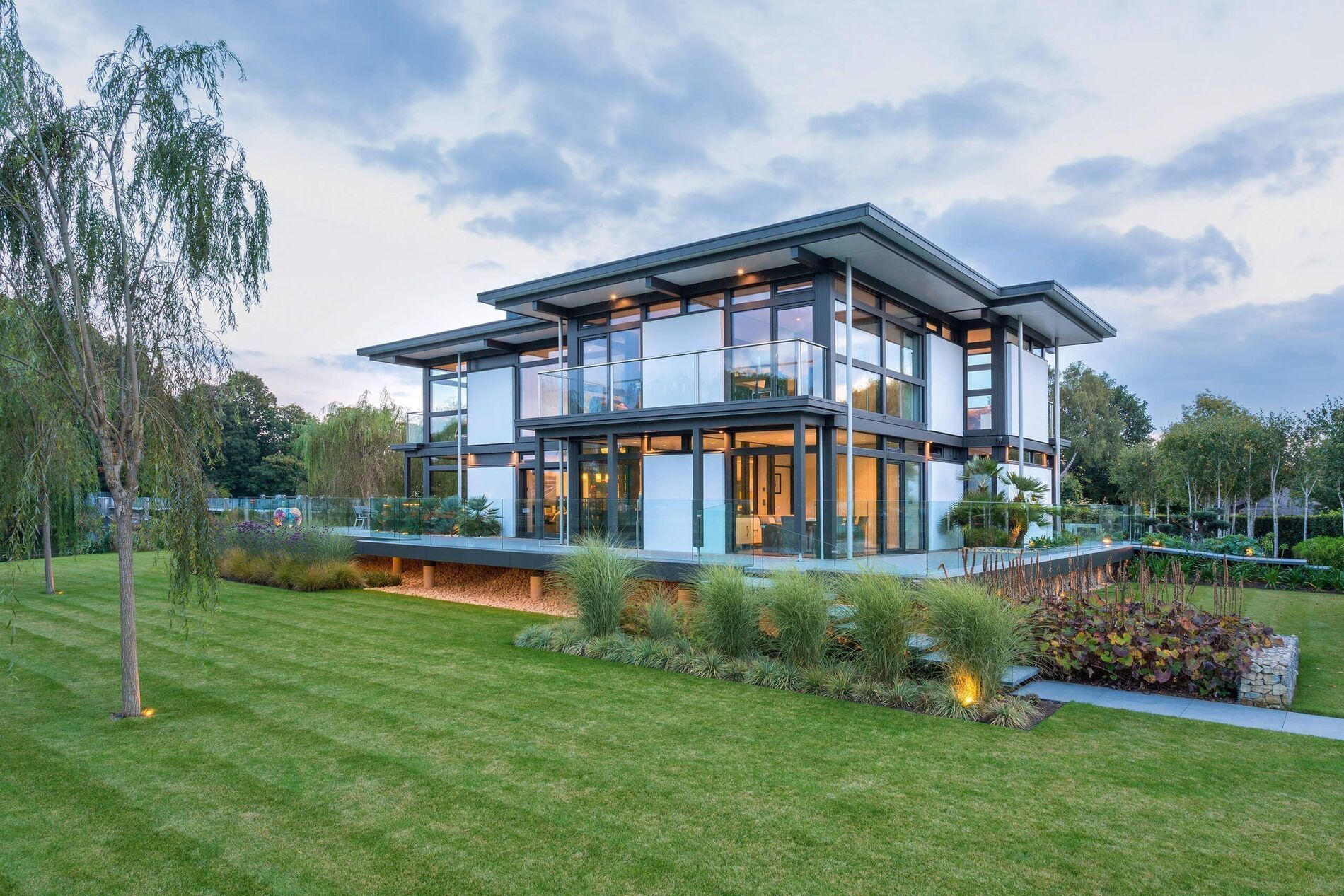 Luxuriöses Haus mit großflächigen Fenstern und gepflegtem Rasen
