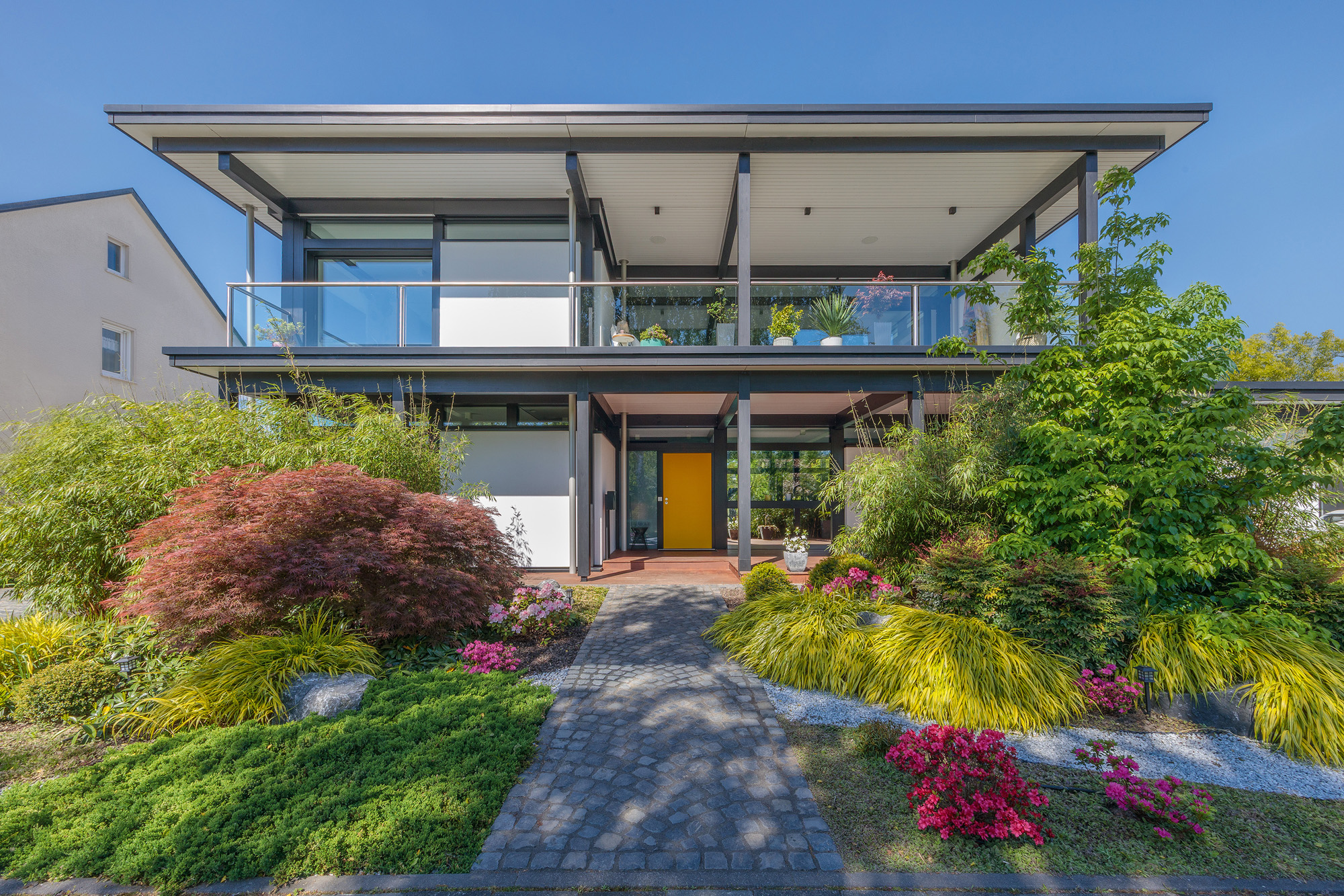 Modernes Designhaus mit Flachdach und Garten Zeitgenössisches Flachdachhaus mit buntem Garten und Terrasse