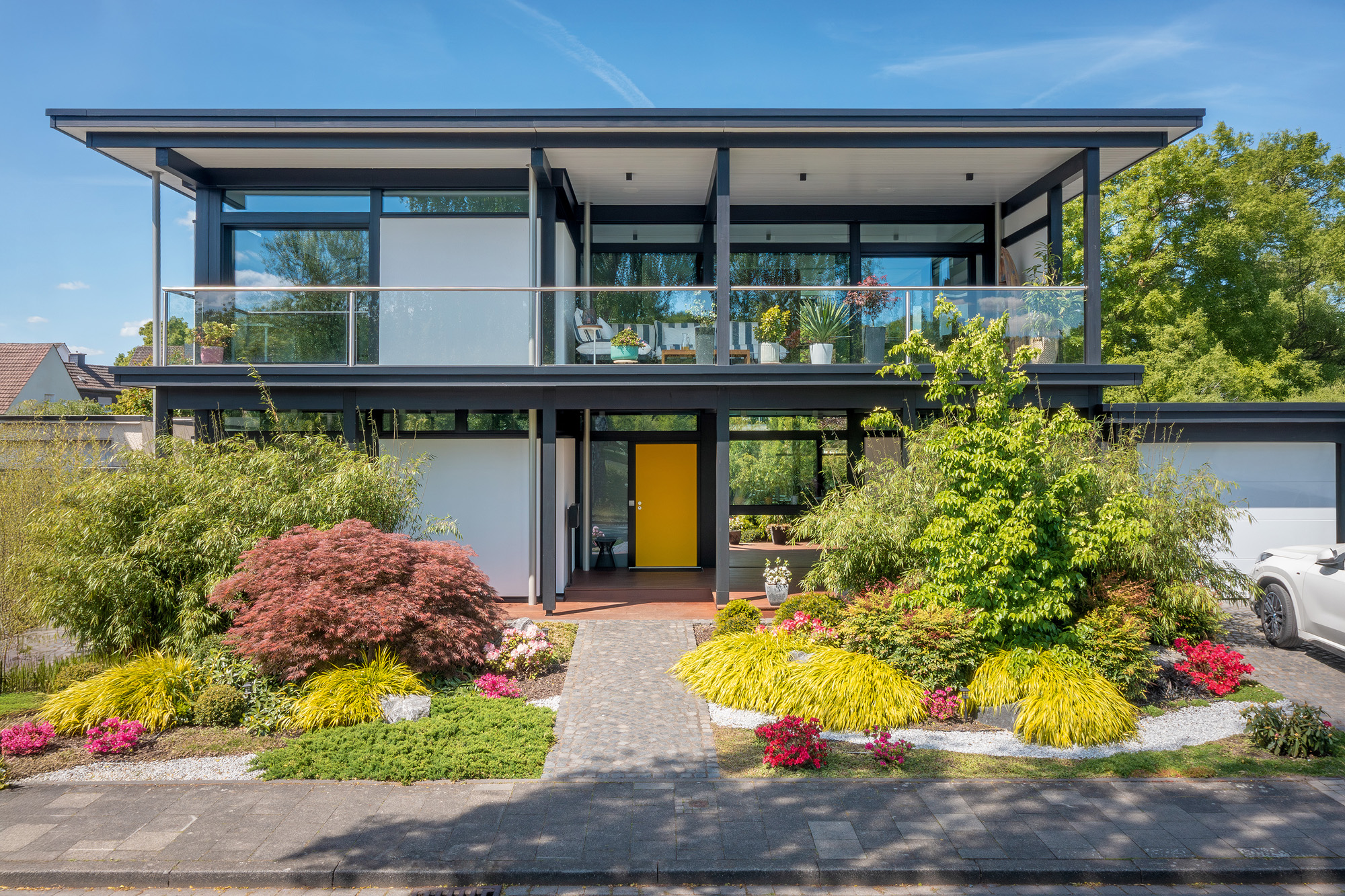 Modernes Designhaus mit Flachdach und gepflegtem Garten HUF Modum Flachdach-Haus mit buntem Garten und Pflanzen