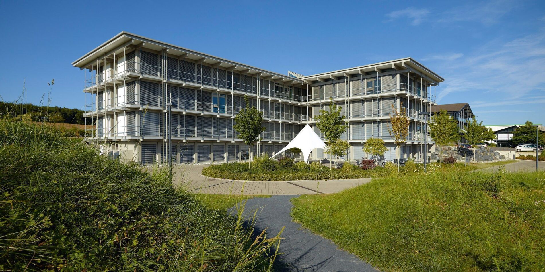 Modernes Bürogebäude HUF in natürlicher Umgebung Bürogebäude HUF mit Grünflächen und blauer Himmel