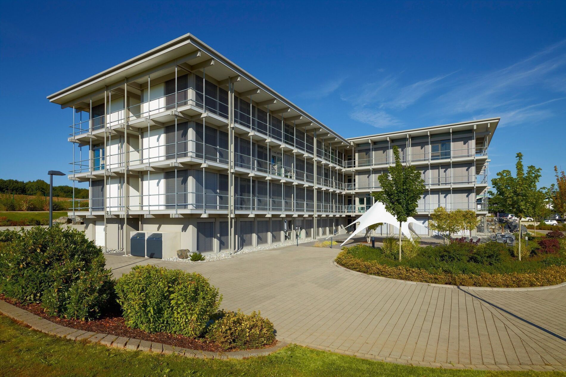 Modernes Bürogebäude HUF mit Glasfassade Bürogebäude HUF umgeben von Grünflächen und klaren Himmel