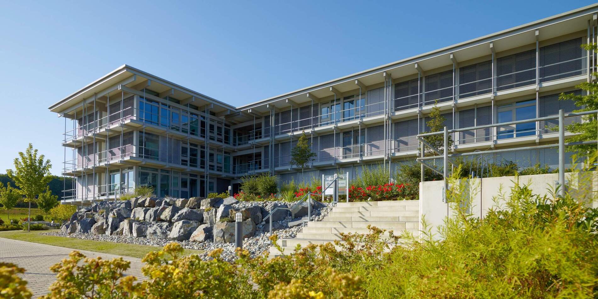 Modernes Bürogebäude HUF mit Gartenanlage Ansicht des Bürogebäudes HUF mit Pflanzen und Treppen
