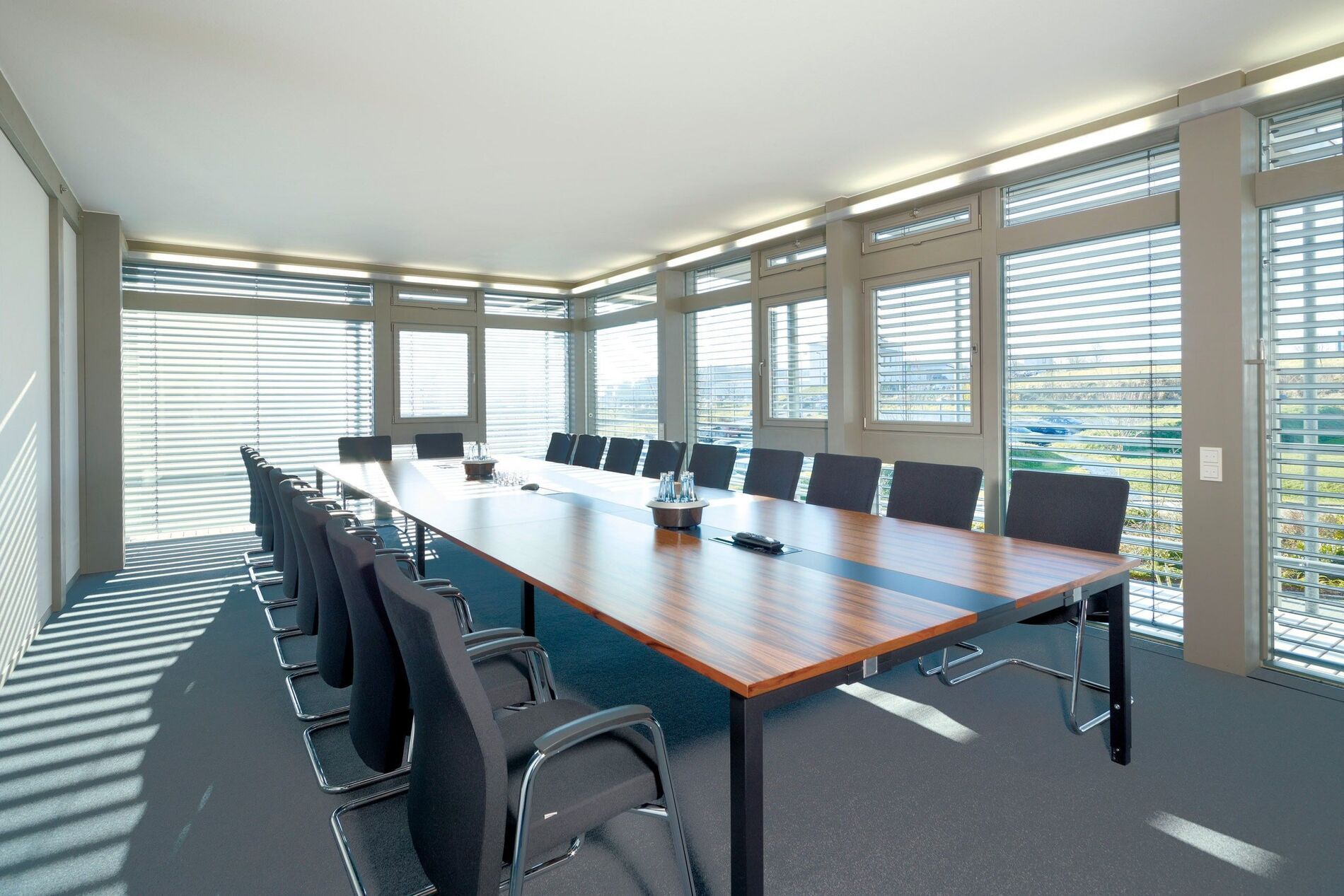 Modernes Bürogebäude mit Konferenzraum Heller Konferenzraum mit großem Tisch und Stühlen, Fenster mit Jalousien