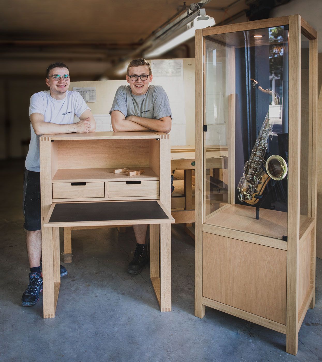 Woodworkers beside a display case showcasing a saxophone