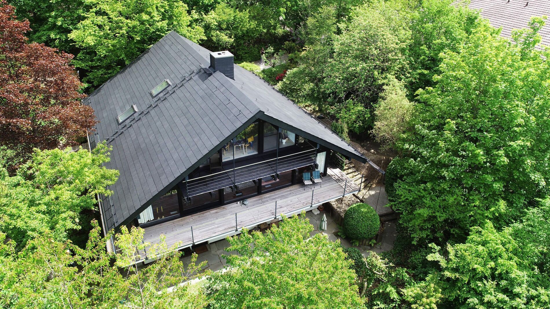 Ein Haus mit schwarzem Dach inmitten von grünem Laub