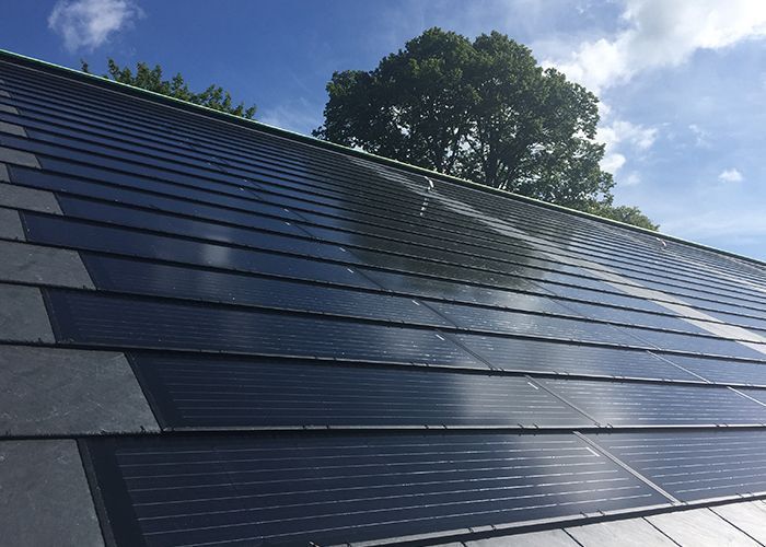 Dach mit Solarzelleninstallation Solarzellen auf einem geneigten Dach unter blauem Himmel