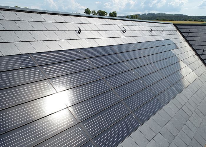 Dach mit Solarpanelen auf schiefergedecktem Haus Moderne Solarpanels auf einem geneigten Dach mit Schiefersteinen