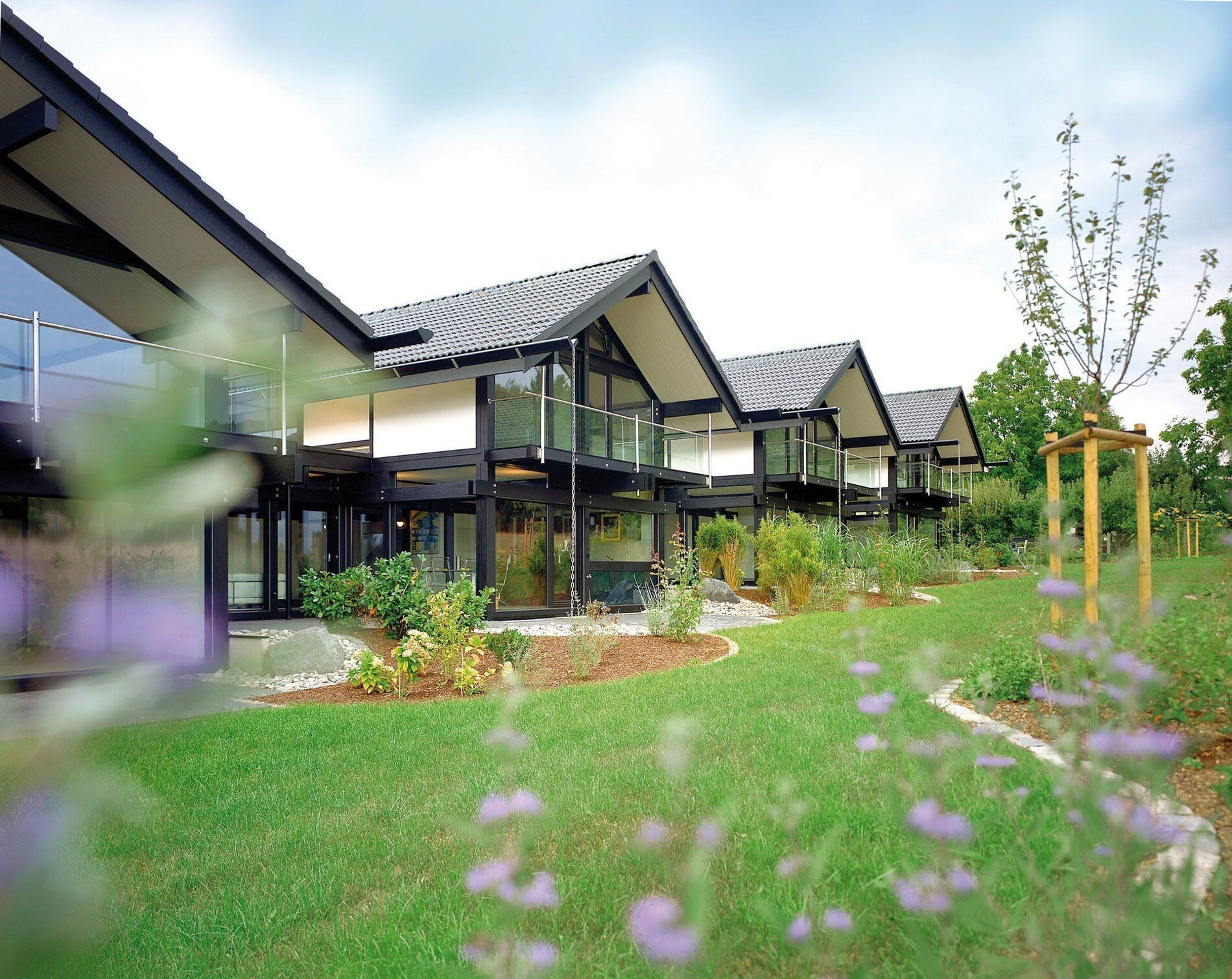 Moderne Wohnhäuser mit Gartenanlage Ansicht von modernen Häusern mit Glasfronten und Garten