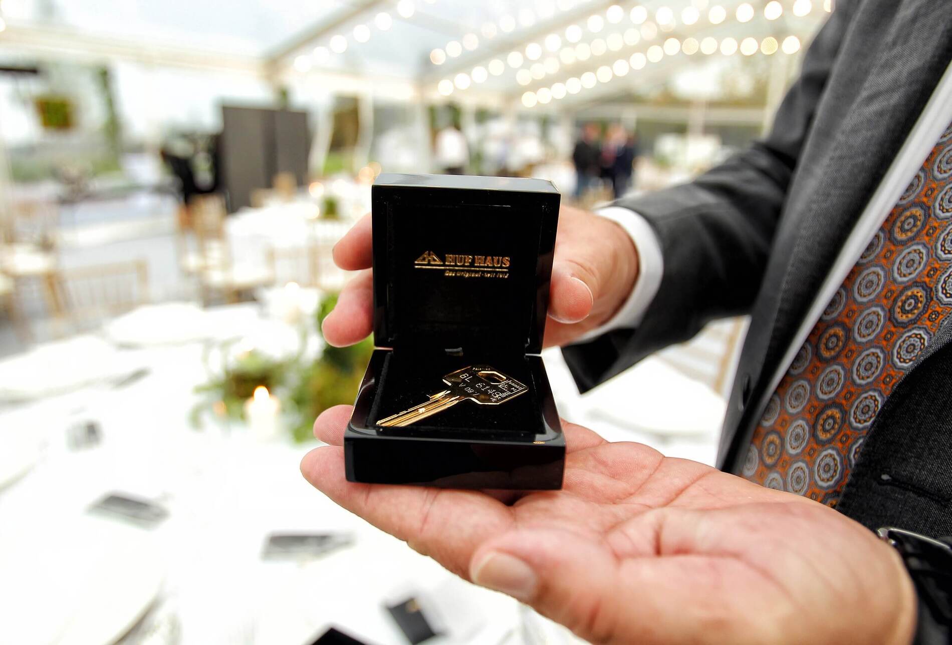 Ein Mann hält einen goldenen Schlüssel in einer Box bei einer Feier