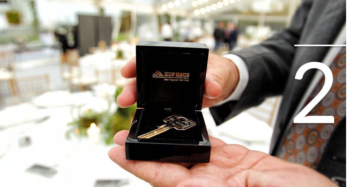 Schlüsselübergabe in eleganter Umgebung Eine Hand hält einen goldenen Schlüssel in einer eleganten Schachtel