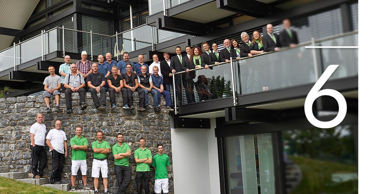 Gruppenfoto vor modernem Gebäude Mehrere Personen posieren vor einem modernen Haus mit Balkonen