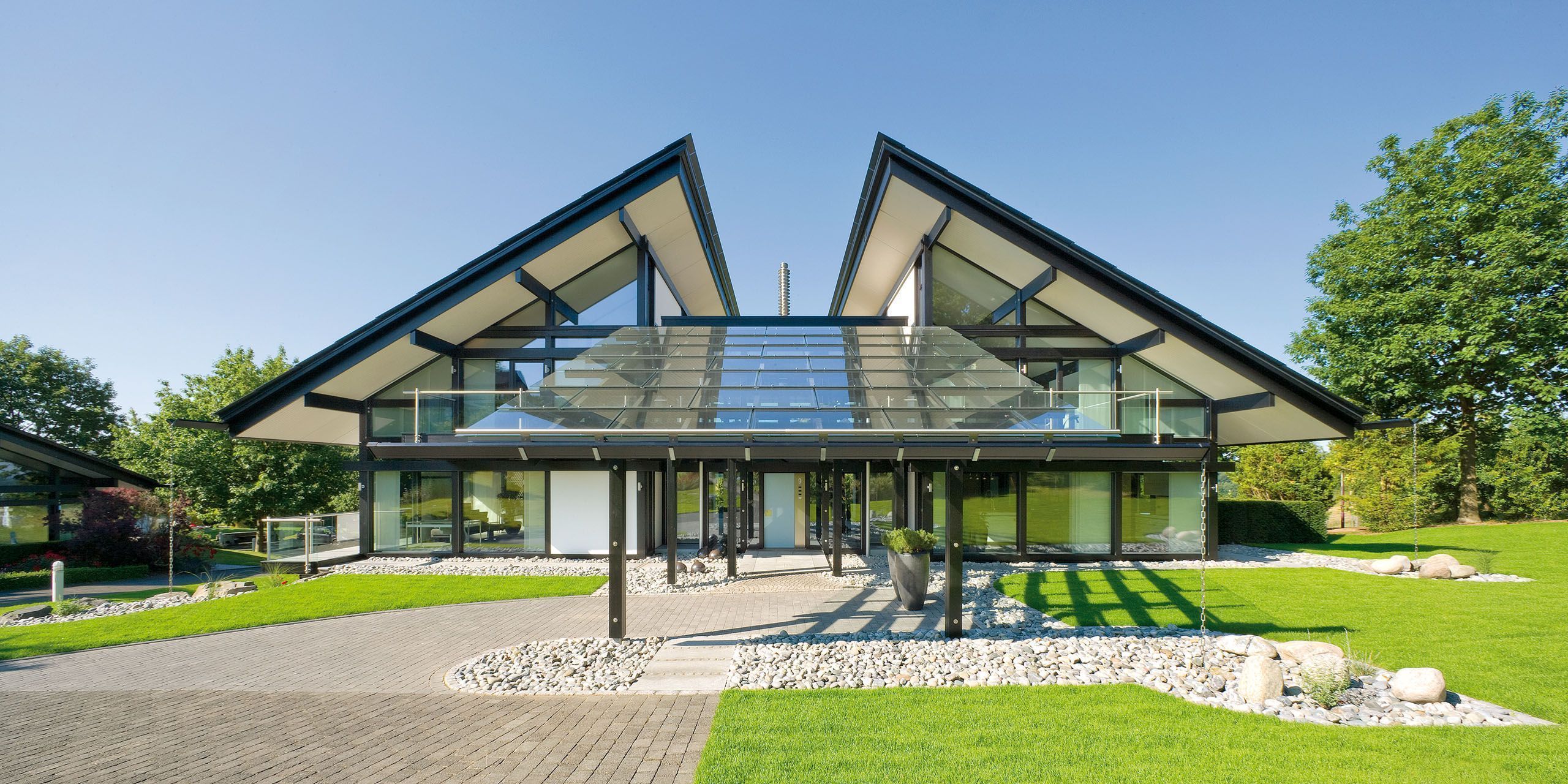 Futuristische Wohnhausfront mit begrüntem Eingangsbereich und Glas-Elementen