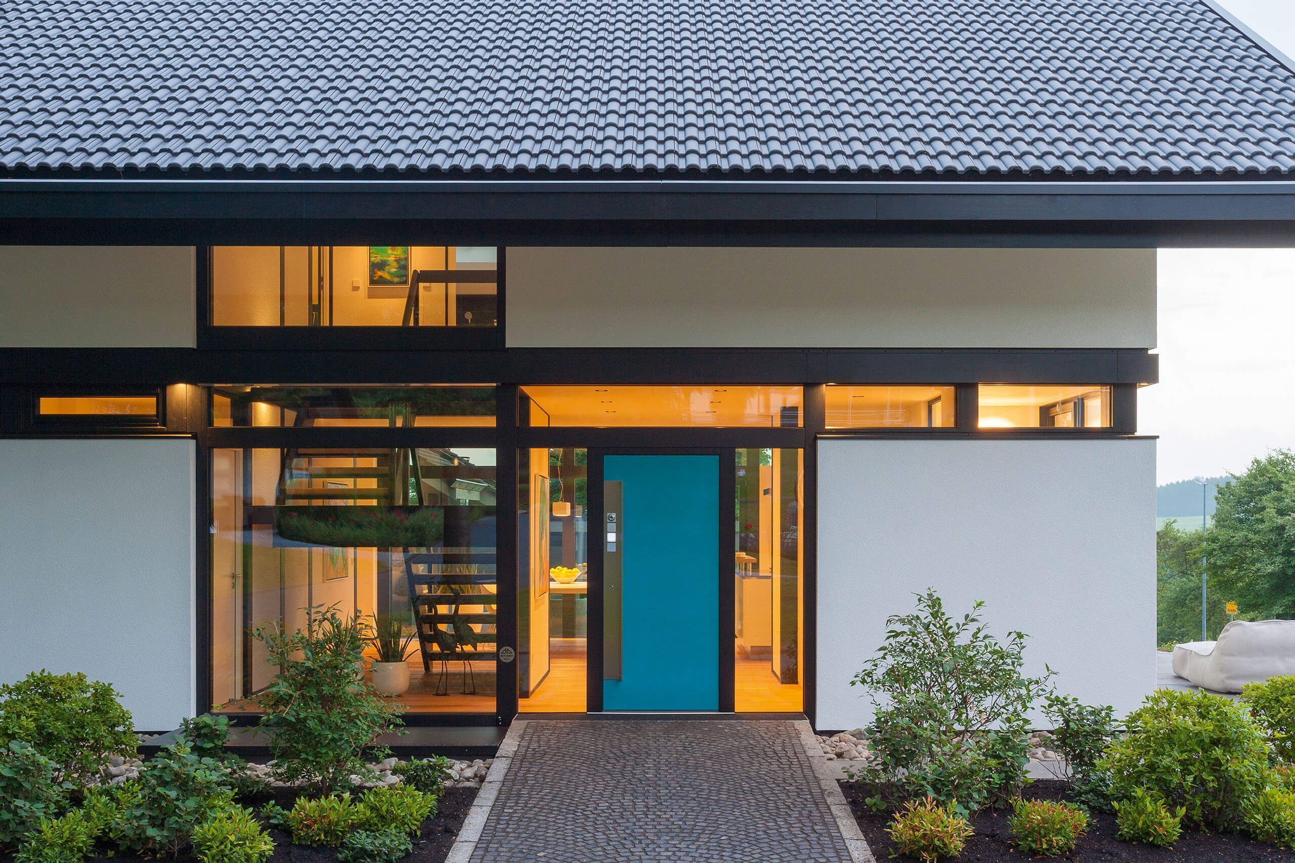 Modum7 10 Eingangsbereich 1 Eingang eines modernen Hauses mit Glasfront und Grünanlagen