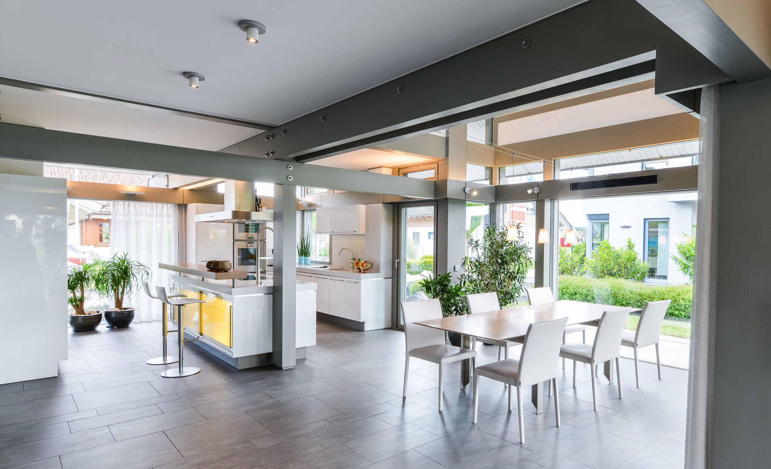 Helle, offene Küche mit Esstisch und Pflanzen im Hintergrund