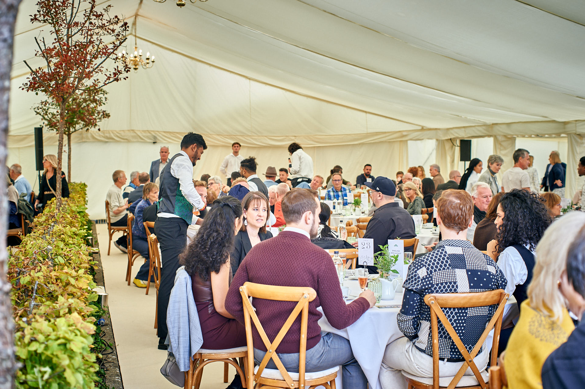 Guests enjoying a meal at round tables in a large tent