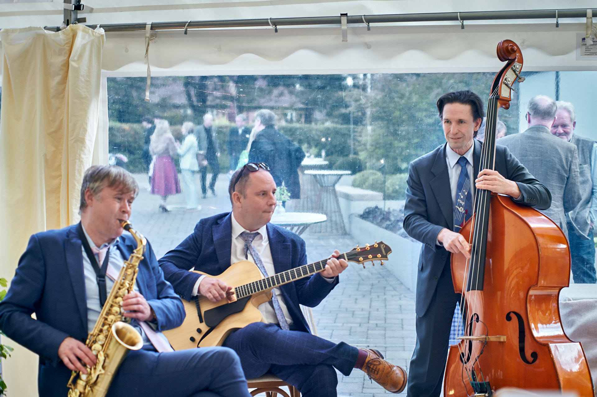 Musicians playing saxophone, guitar, and double bass indoors