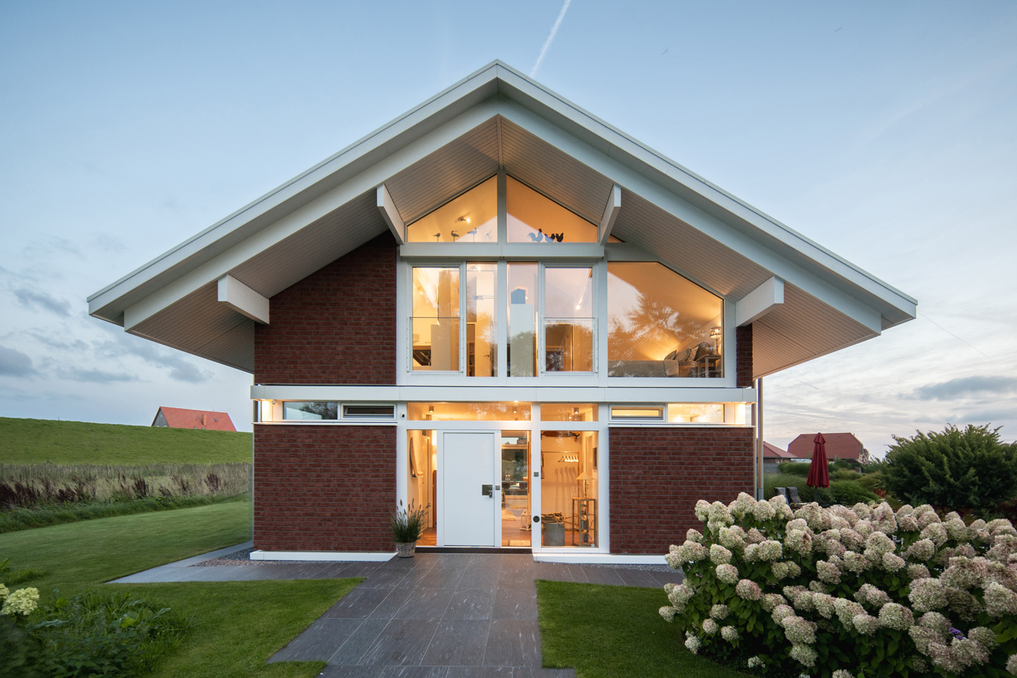 Haus mit großen Fenstern und ansprechender Gartenlandschaft