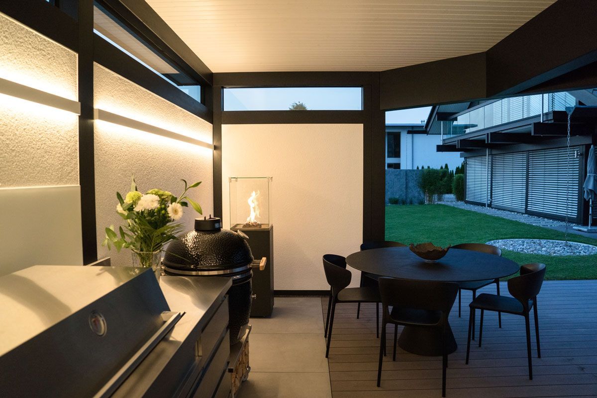 Elegante Terrasse mit Grill, Tisch und Garten im Hintergrund