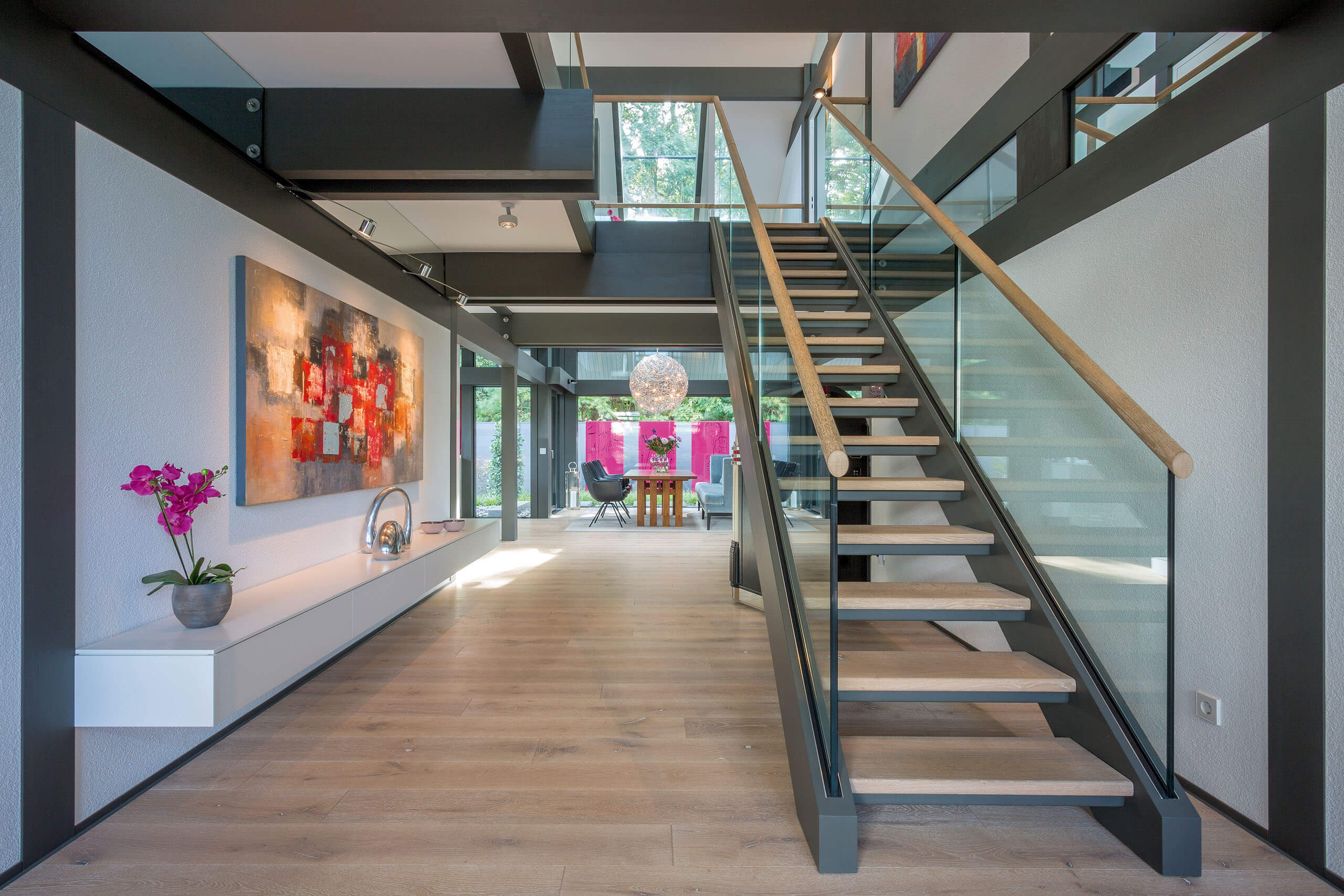 Moderne Treppe in einem lichtdurchfluteten Raum Heller Eingangsbereich mit Treppe und moderner Kunst an der Wand