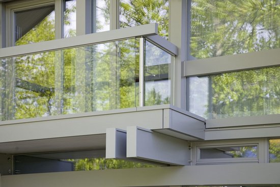 Moderne Architektur mit Glasbalustrade und Ausblick Detailaufnahme einer modernen Fassade mit Glas und Pflanzenreflexionen