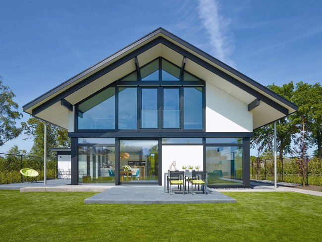 Haus mit Glasfassade und einem grünen Garten in sonniger Umgebung