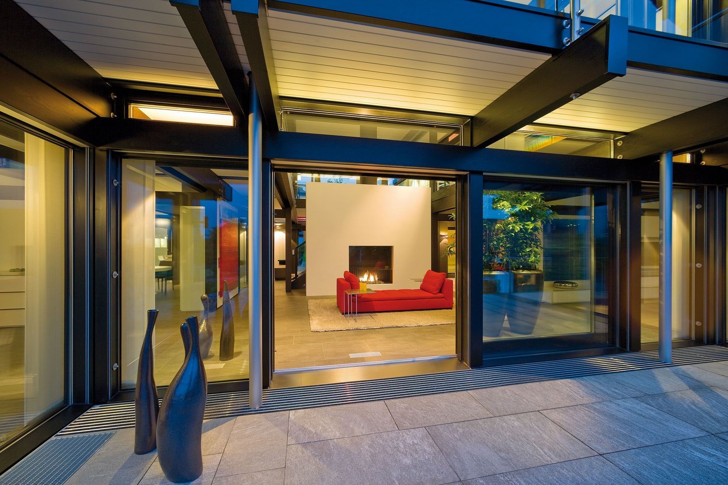 HUF Dorf Musterhauszentrum ART 9 15 Einblick in ein modernes Wohnzimmer mit rotem Sofa und Kamin