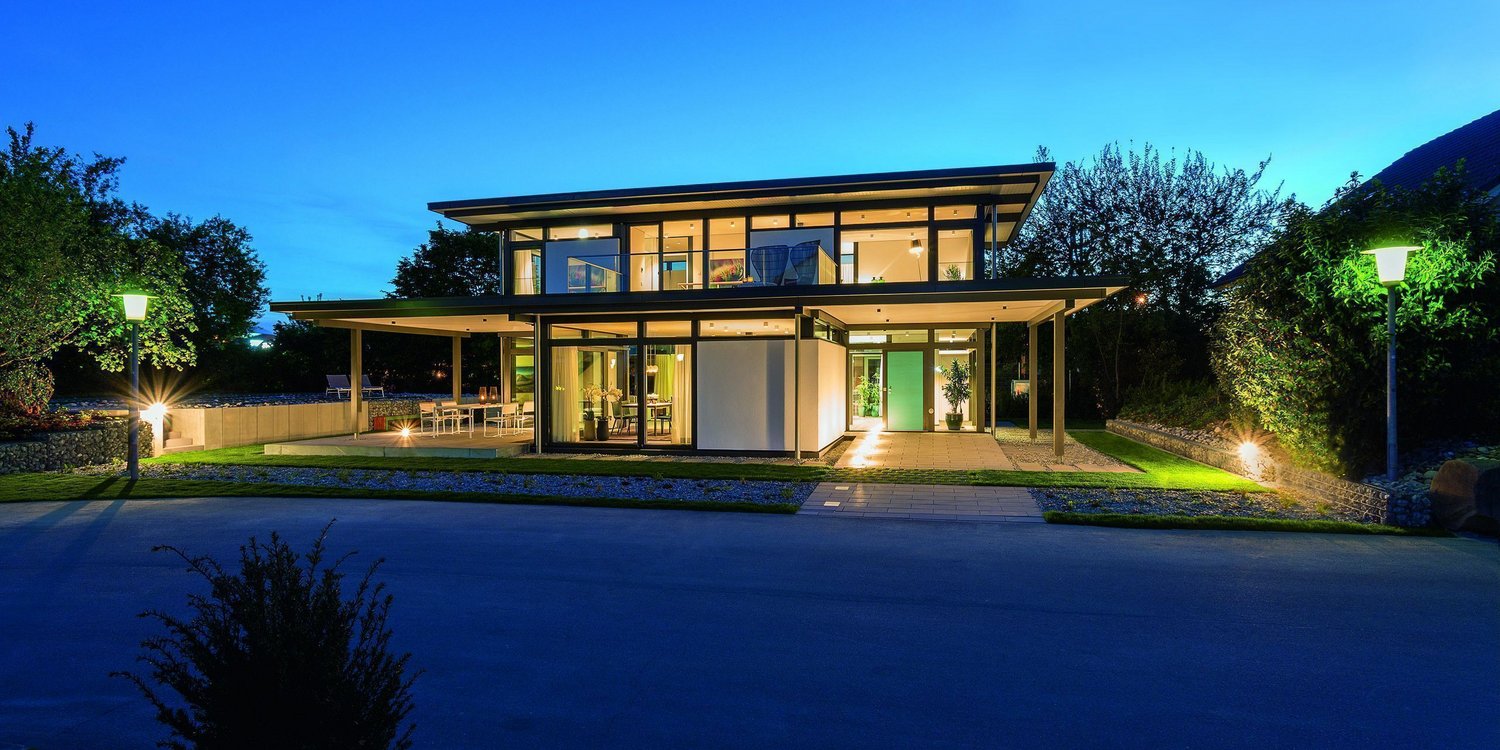 Moderne Villa bei Nacht mit Garten und Außenbeleuchtung Schöne moderne Architektur einer Villa umgeben von grünen Bäumen
